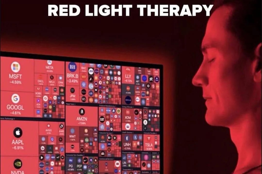Man sitting in front of a screen full of red market tickers captioned red light therapy.