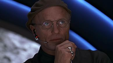 Man in a beanie and round glasses wearing a headset mic, looking calculating, used as the market maker secretly controlling crypto prices.
