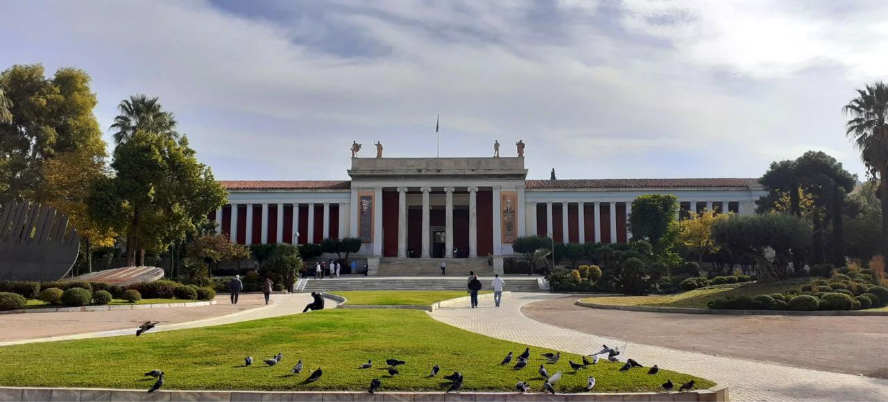Bronze ancient Greek sculptures and gold artifacts displayed in museum gallery case.