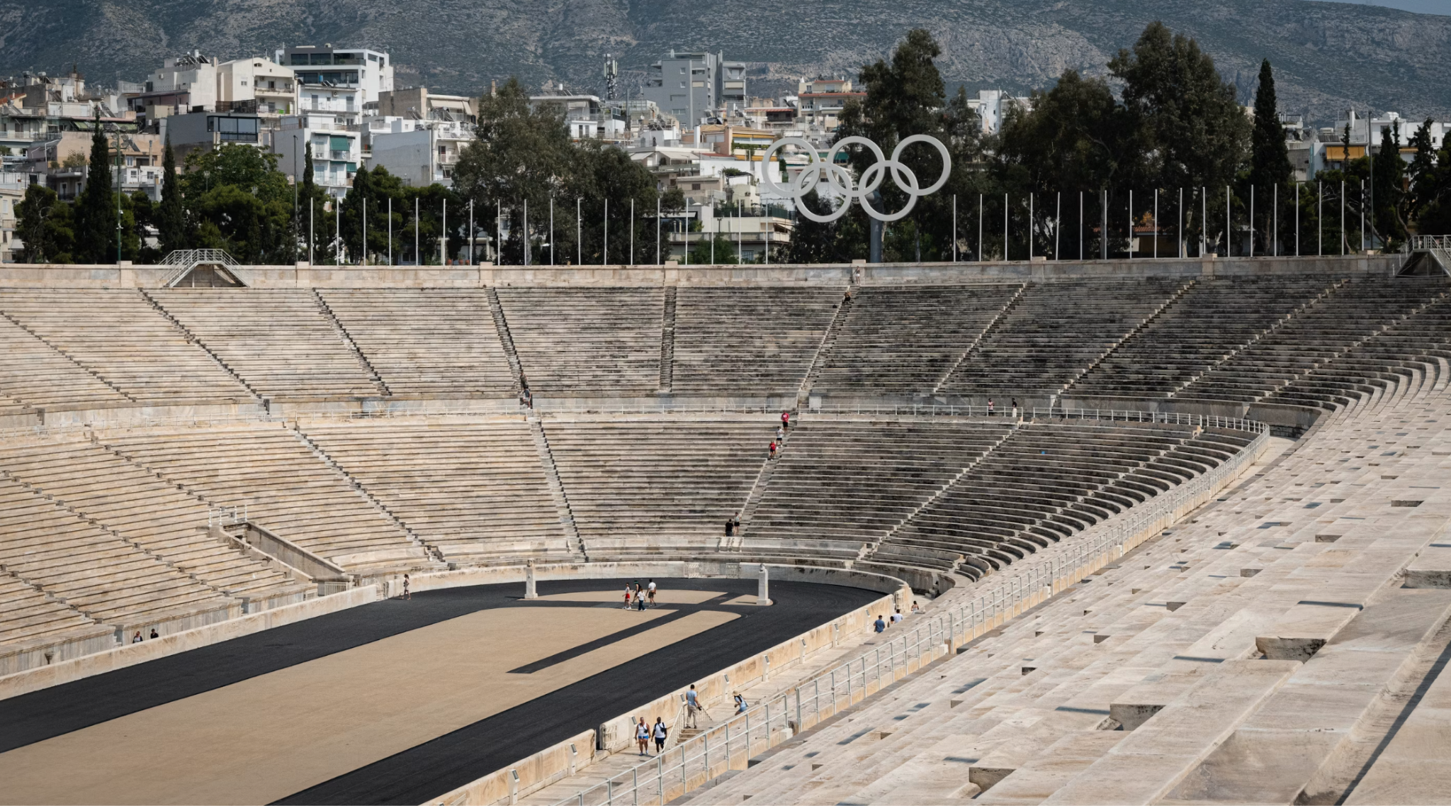 White marble Panathenaic Stadium oval track with tiered seating under blue sky.