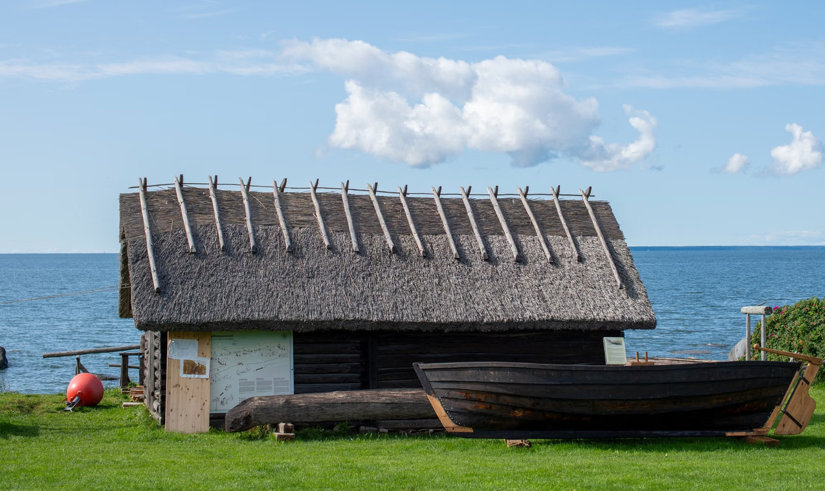 Thatched fishing hut and wooden boat beside calm Baltic Sea