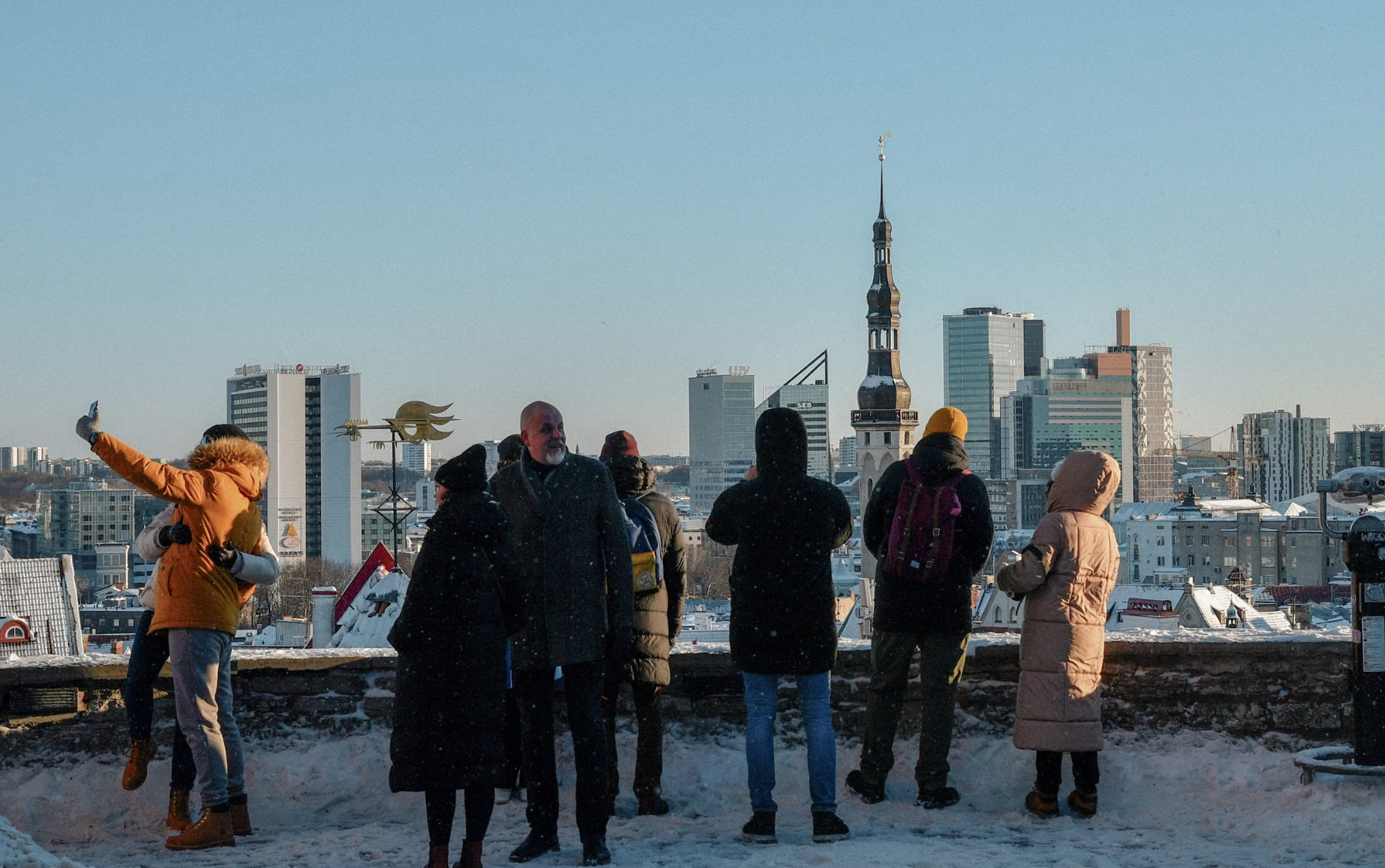 Tourists photographing snowy Tallinn skyline from Toompea viewing platform