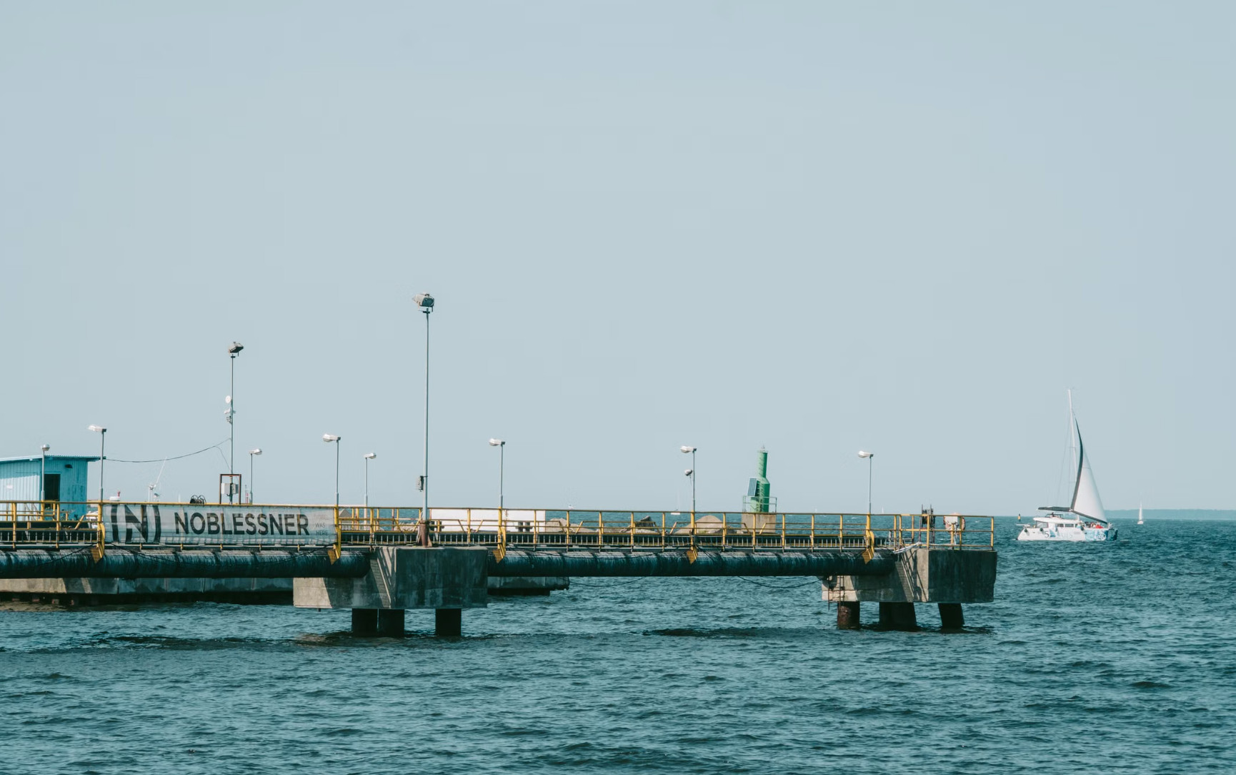Noblessner seafront pier with moored sailboat under clear Baltic sky