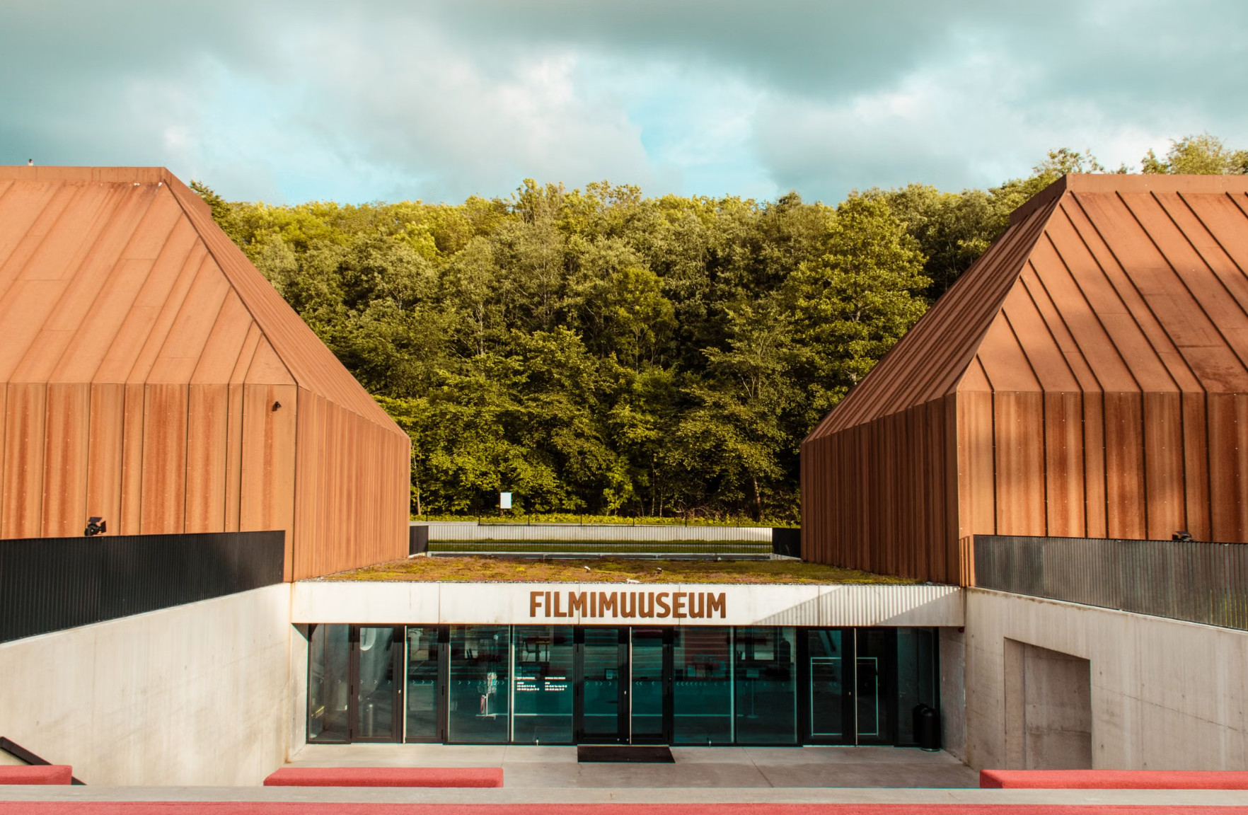Estonian Film Museum copper building beside forest under cloudy sky