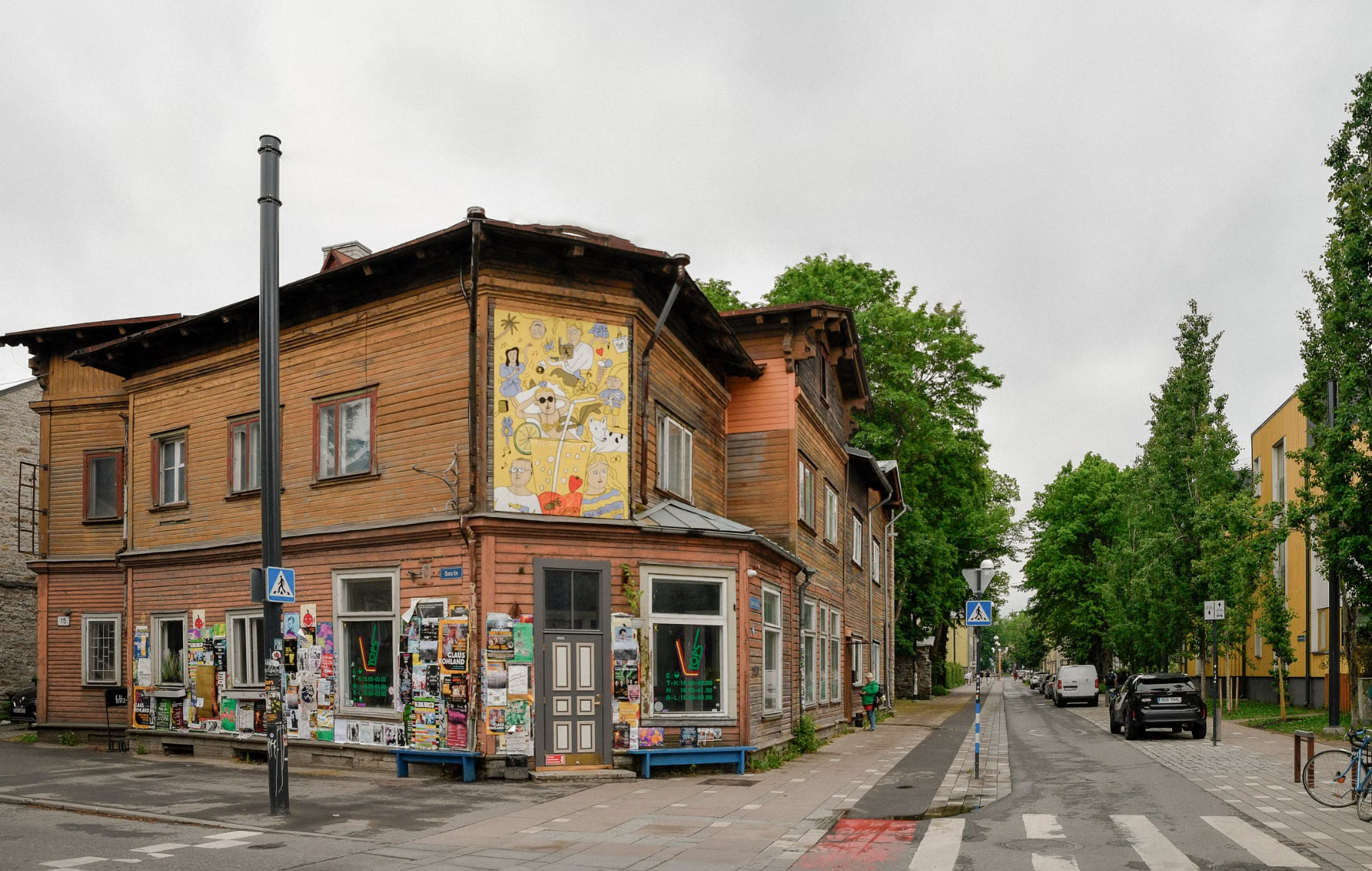 Colourful wooden Kalamaja corner house covered with posters and mural