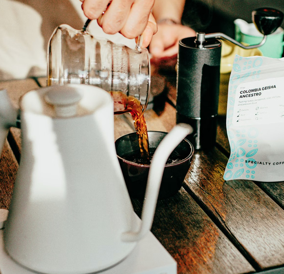 Pouring freshly brewed Geisha specialty coffee into small cup