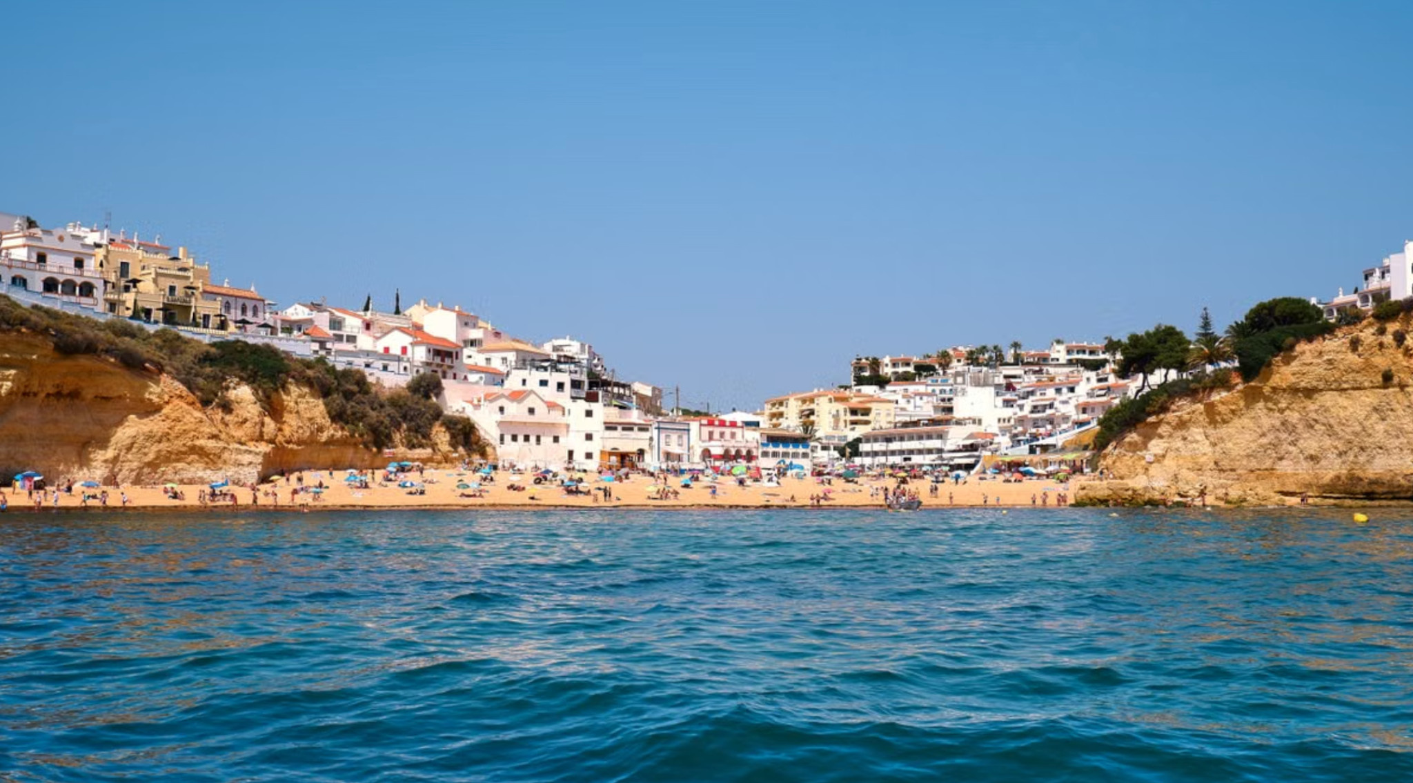 Whitewashed Carvoeiro town above busy cove beach in central Algarve