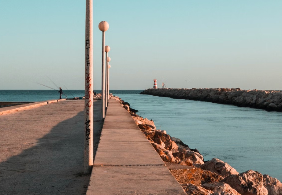 Angler on pier by lighthouse at Faro harbour, Algarve