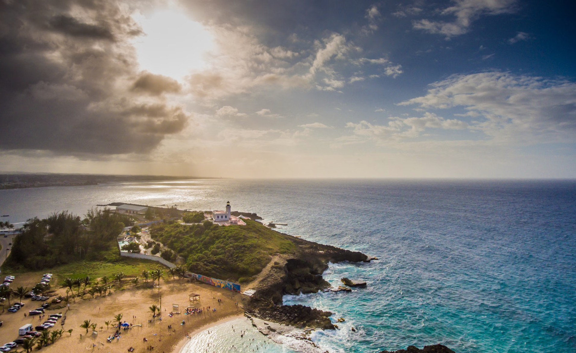 Aerial coastal lighthouse on green point beside turquoise sea