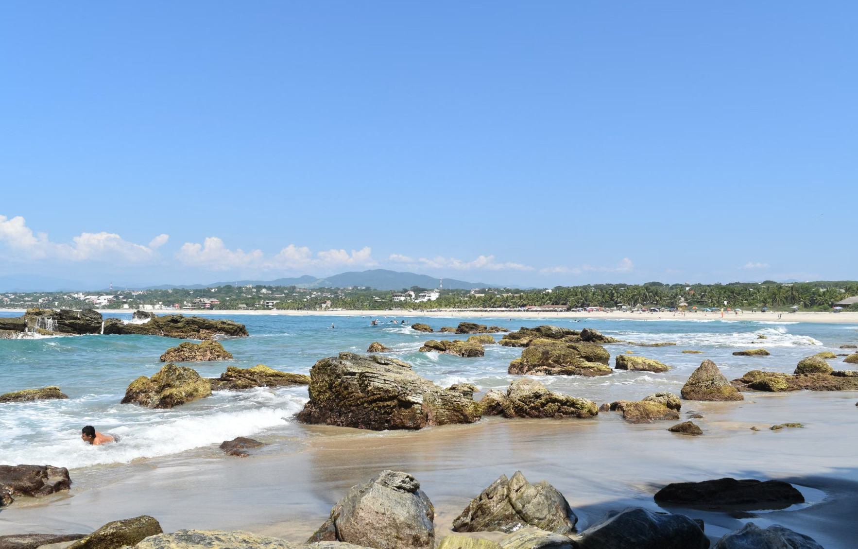 Rocky sandy beach with waves and distant coastal town