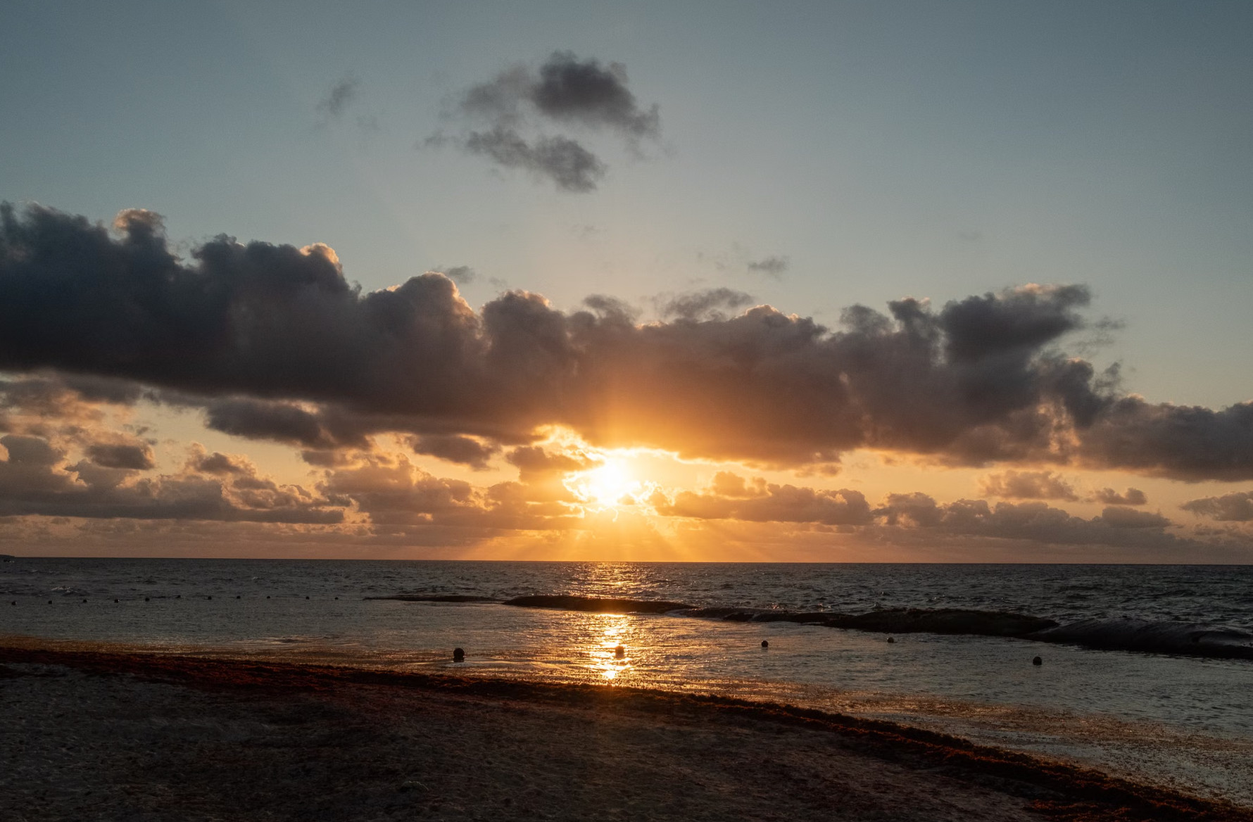 Golden sunset over calm ocean horizon and rocky shoreline