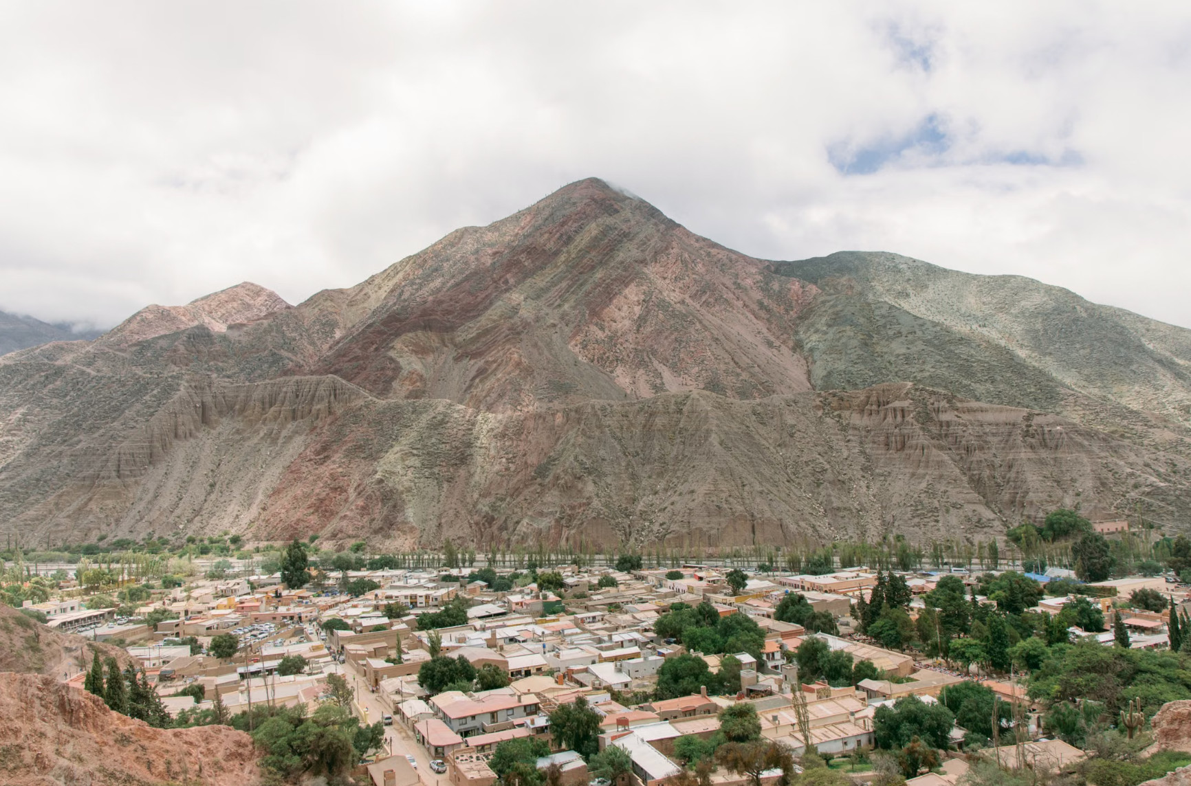 Andean town nestled below layered multicoloured mountain in Argentina