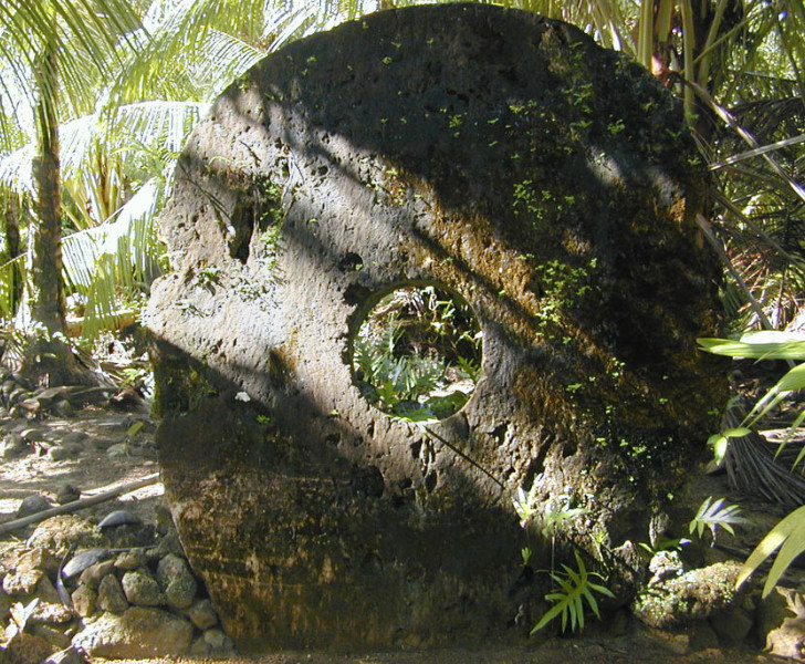 Giant Yapese stone money disc among tropical jungle plants