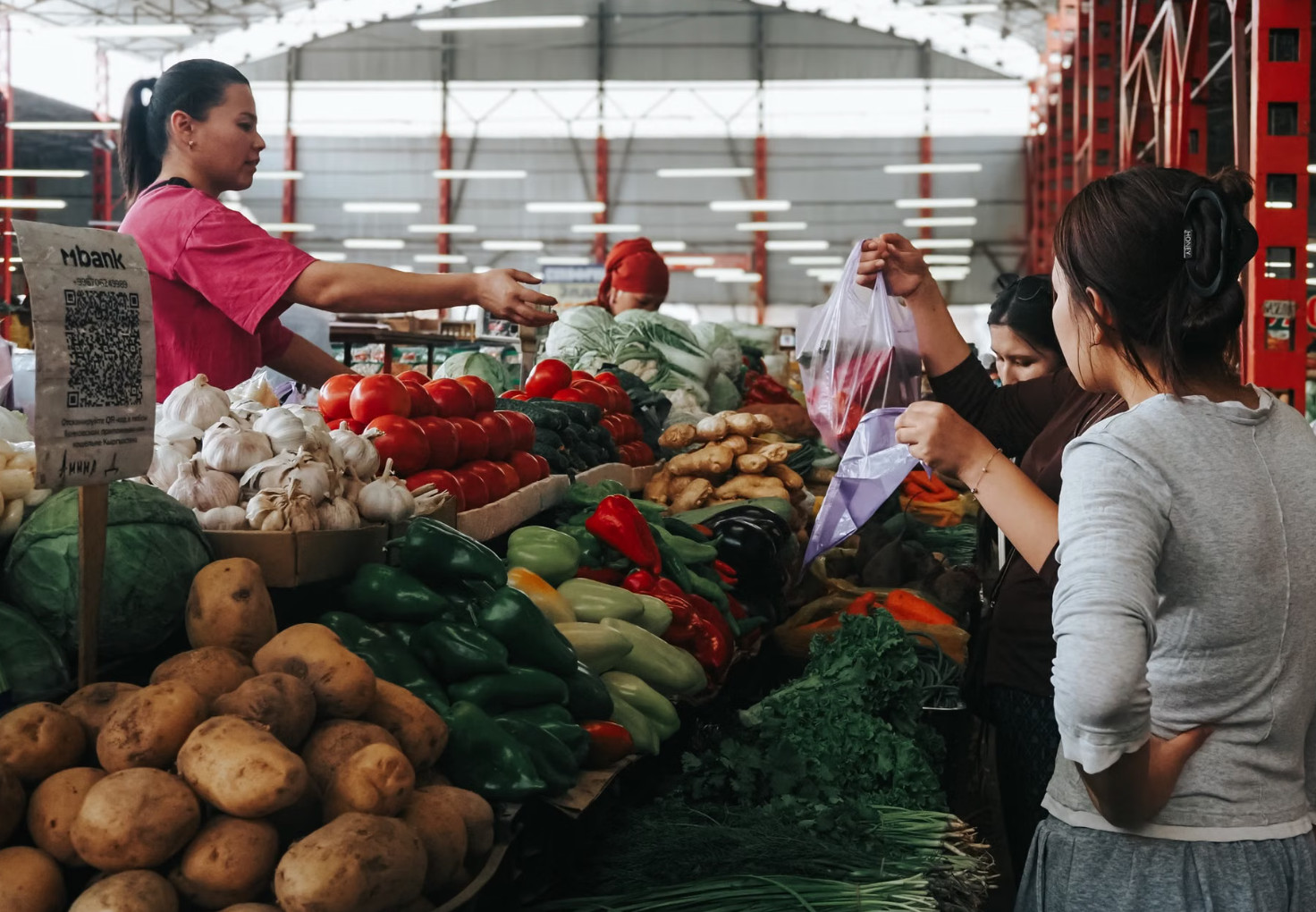Vendor selling fresh vegetables at busy covered market stall
