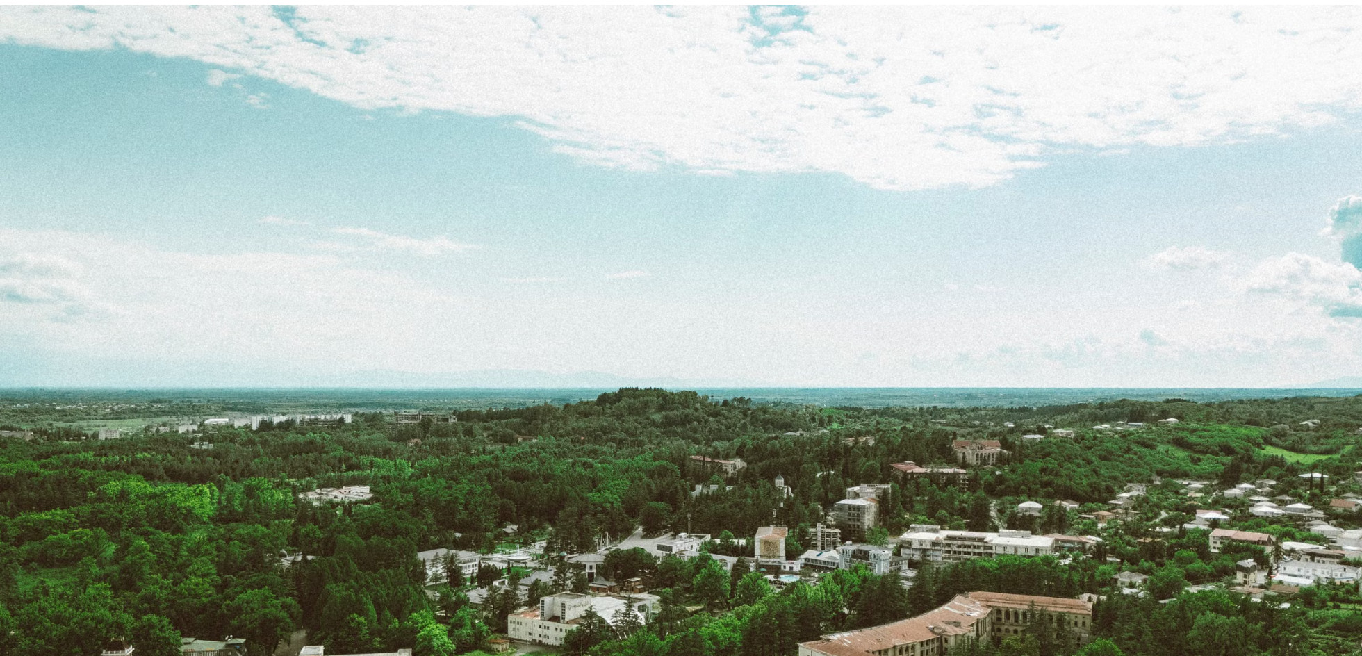 Aerial view of leafy town among green forested hills