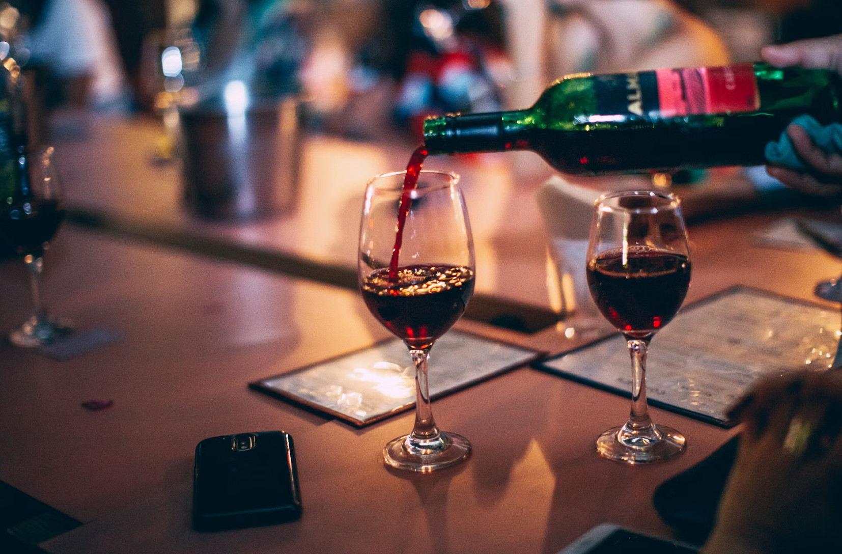 Red wine poured into glasses at candlelit wine bar