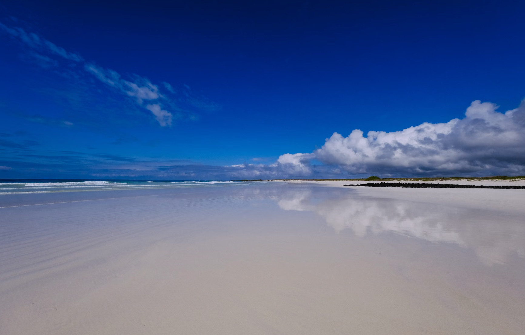 Empty white sand beach under bright blue Galápagos sky