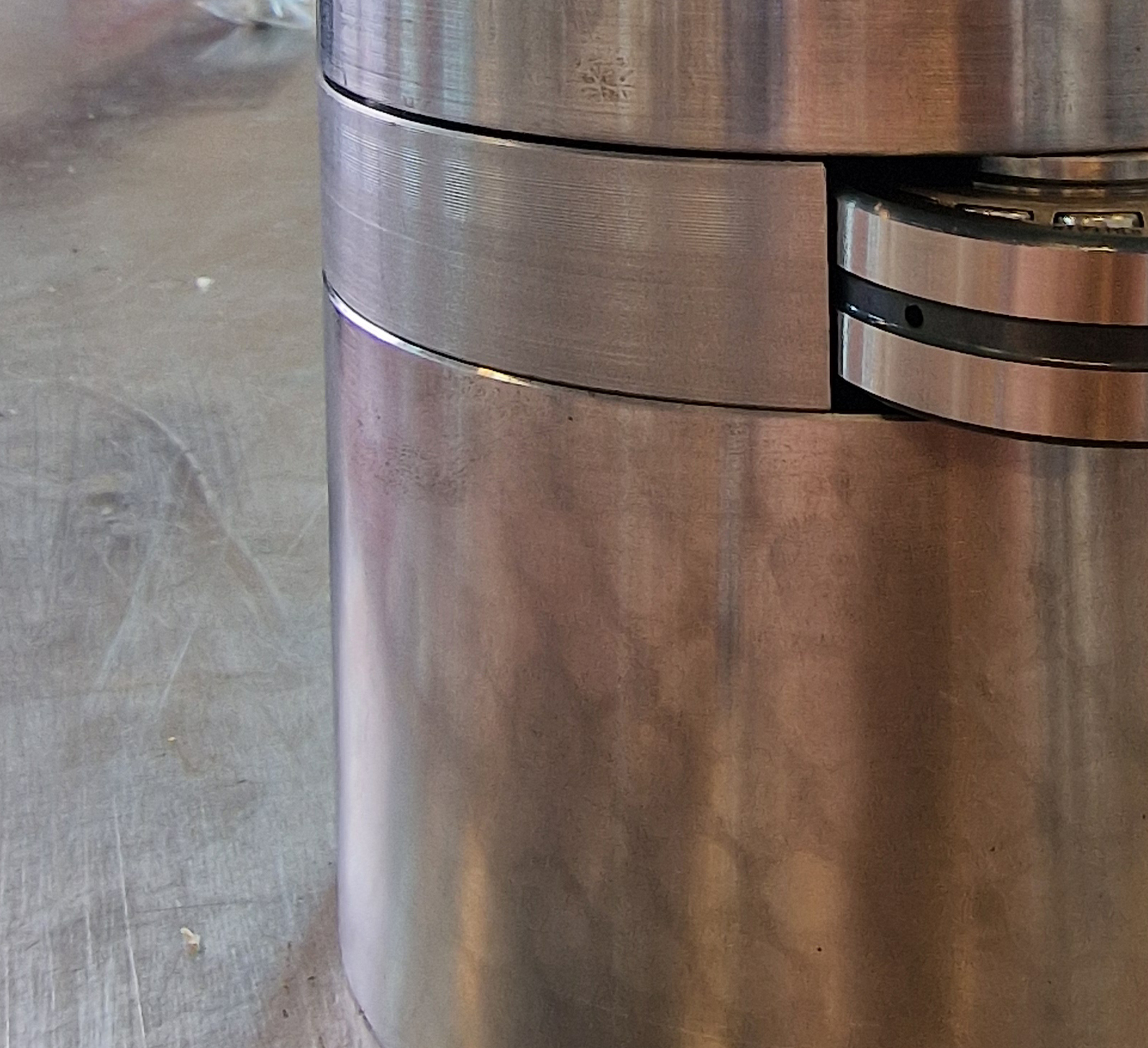 Close-up of metallic cylindrical compressor parts with smooth and grooved surfaces on a metal table.