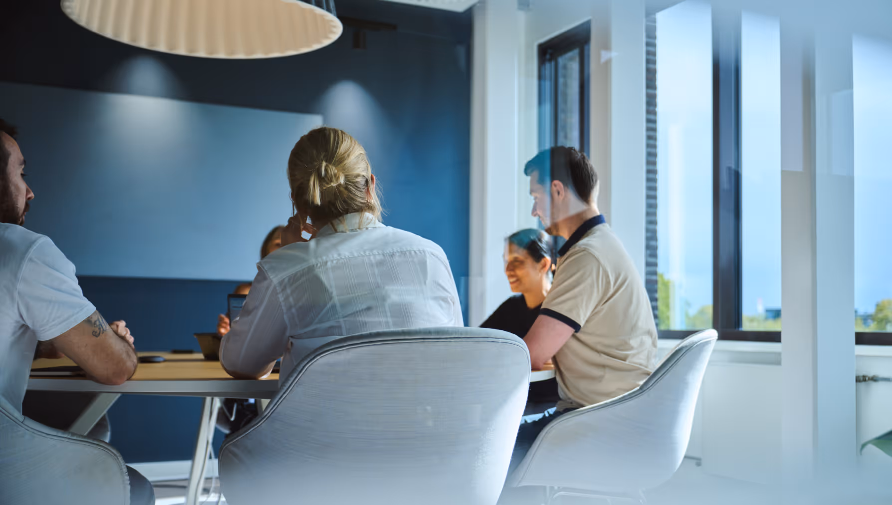 A group of four people sitting around a table in a bright modern office having a discussion.