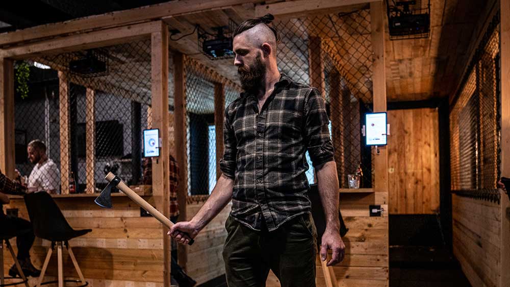Man met geruit overhemd houdt een bijl vast bij Antwerp Axe Throwing