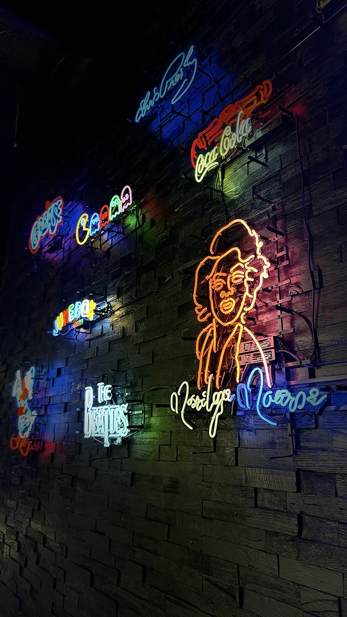Neonlichten met Marilyn Monroe, The Beatles, Coca-Cola en Pac-Man op een donkere bakstenen muur.