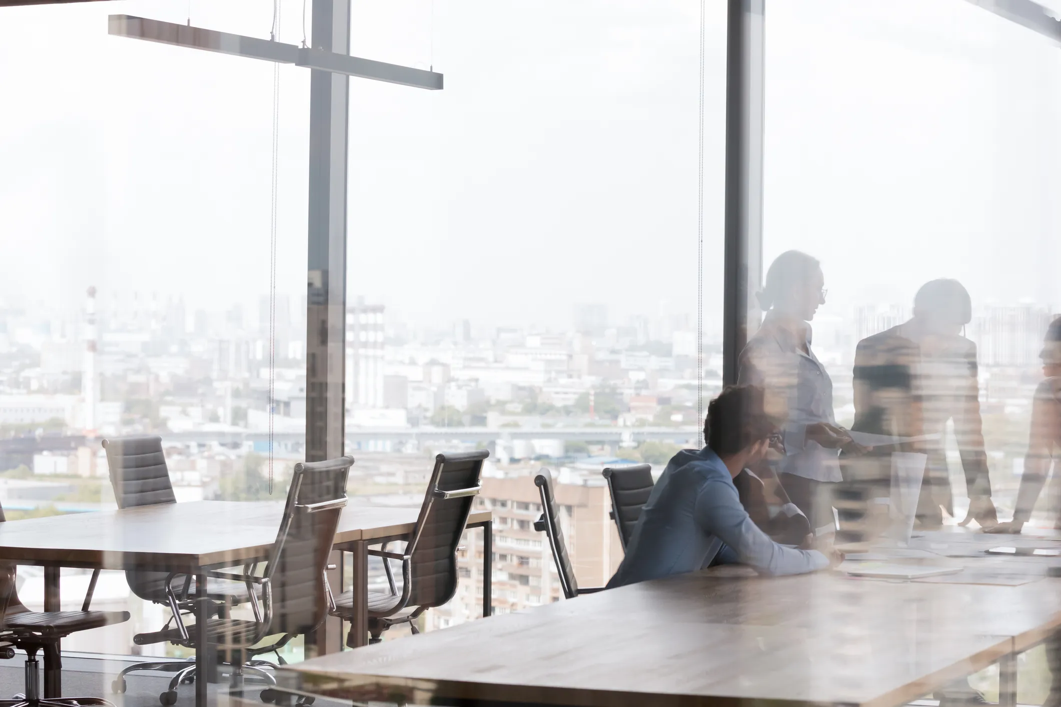 Office conference room with glass walls and a group of people having a meeting inside.