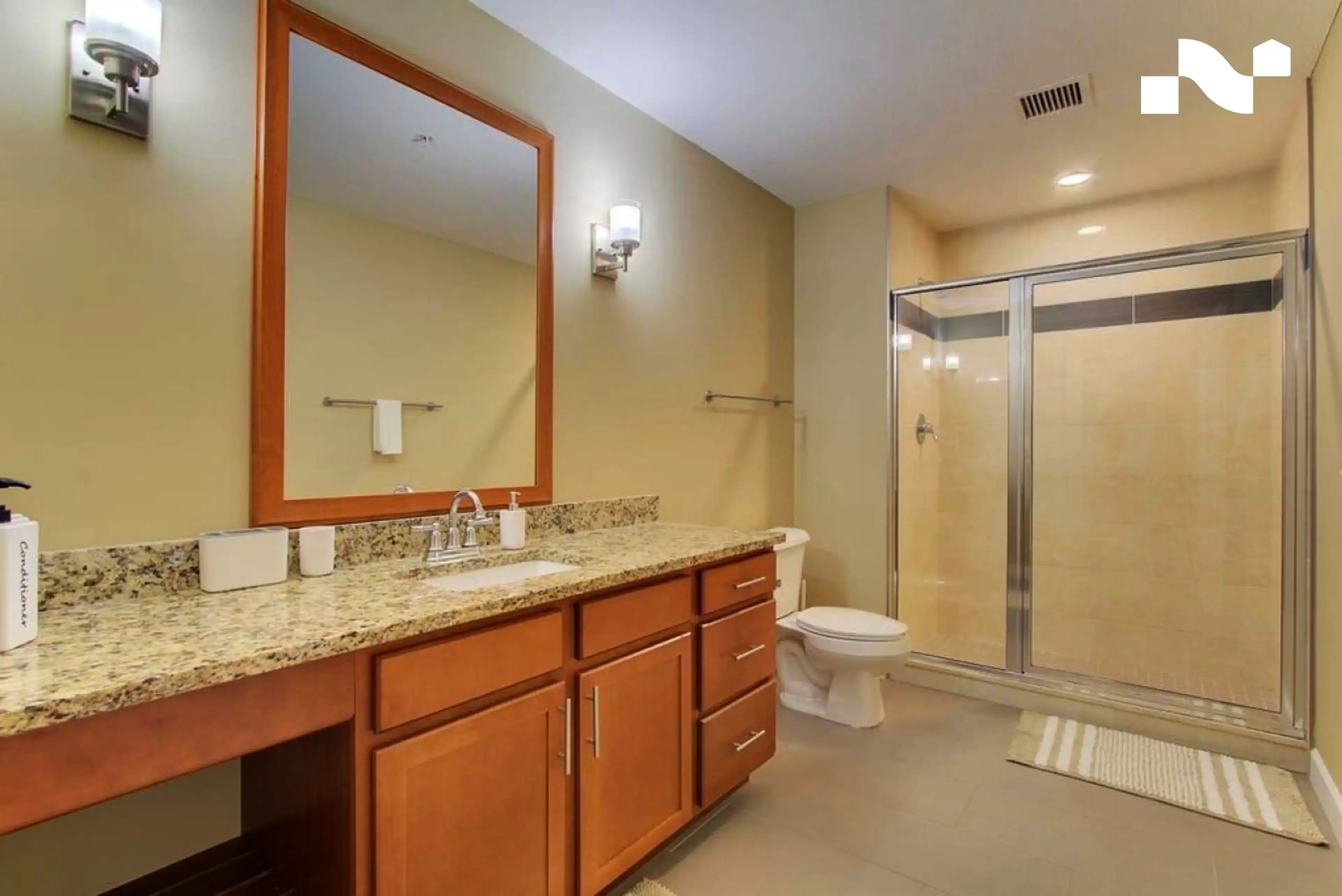 Step-in shower with a low threshold beside a long vanity in a furnished Nearwell apartment bathroom near Cleveland Clinic