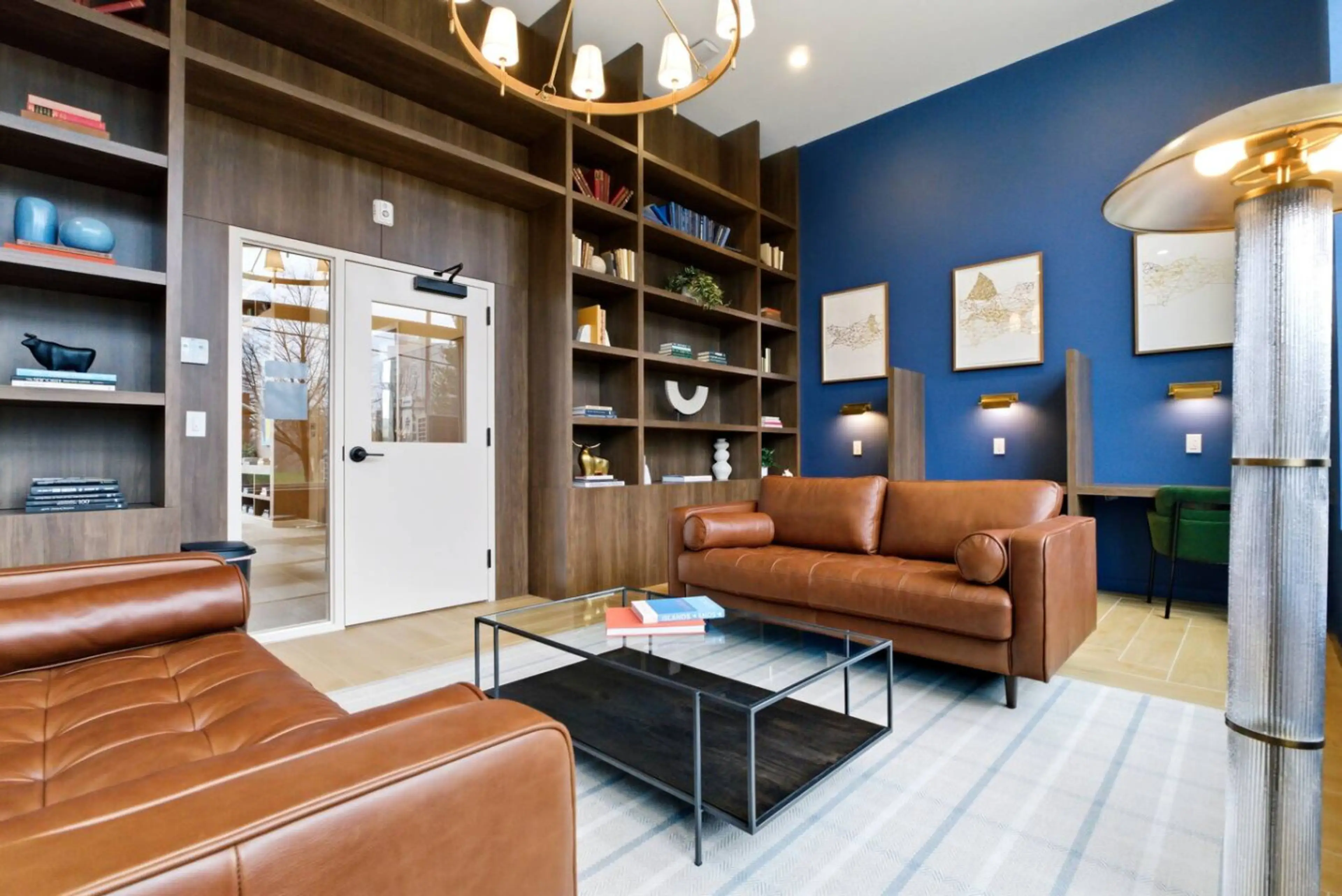 Modern living room with two gray couches, wooden coffee table, blue accent wall, and large windows.