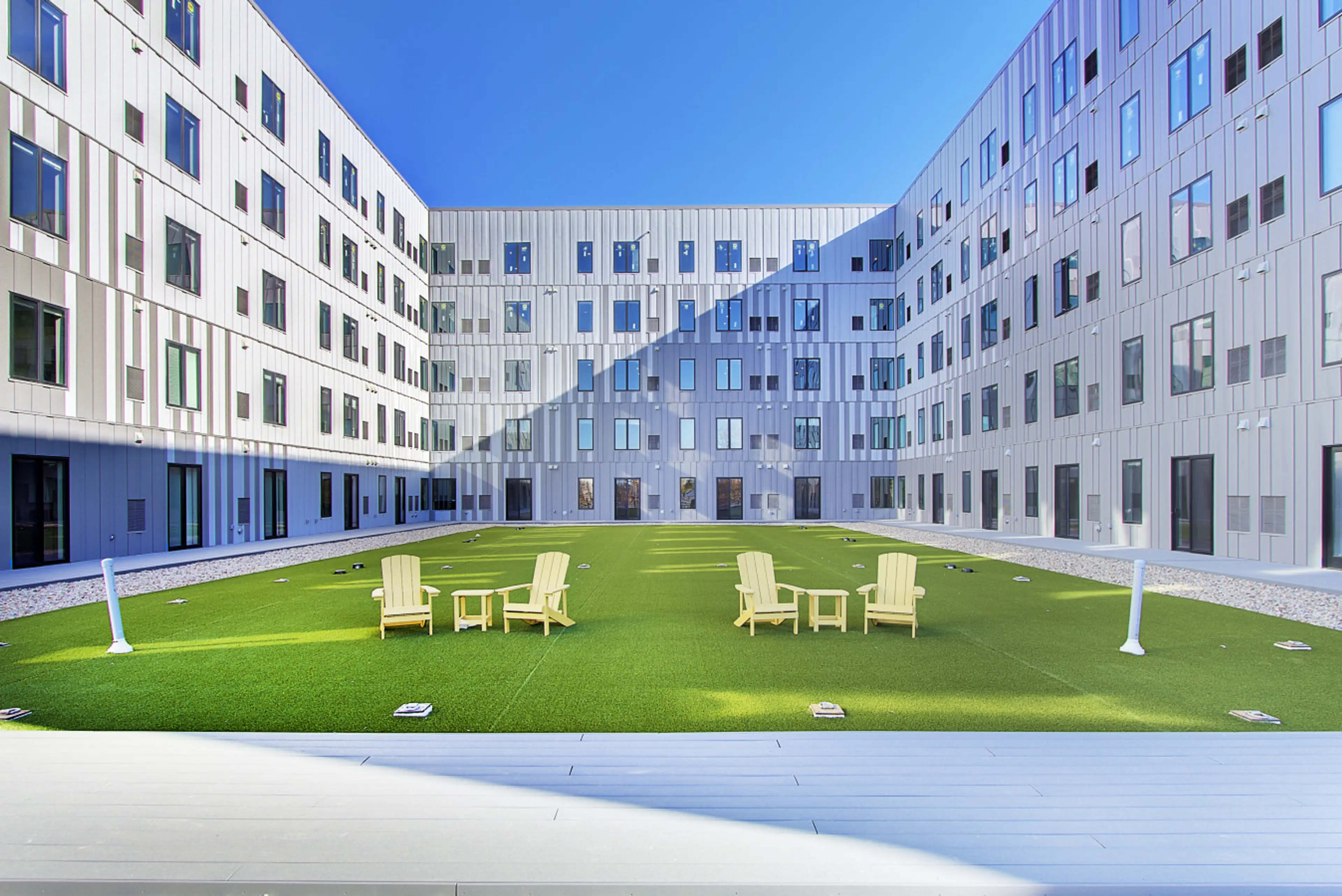 Interior courtyard with a lawn and chairs surrounded by apartment windows