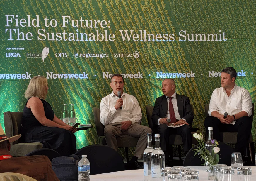 A four-person panel on stage at the Field to Future Sustainable Wellness Summit, Regenagri among the partner logos behind them