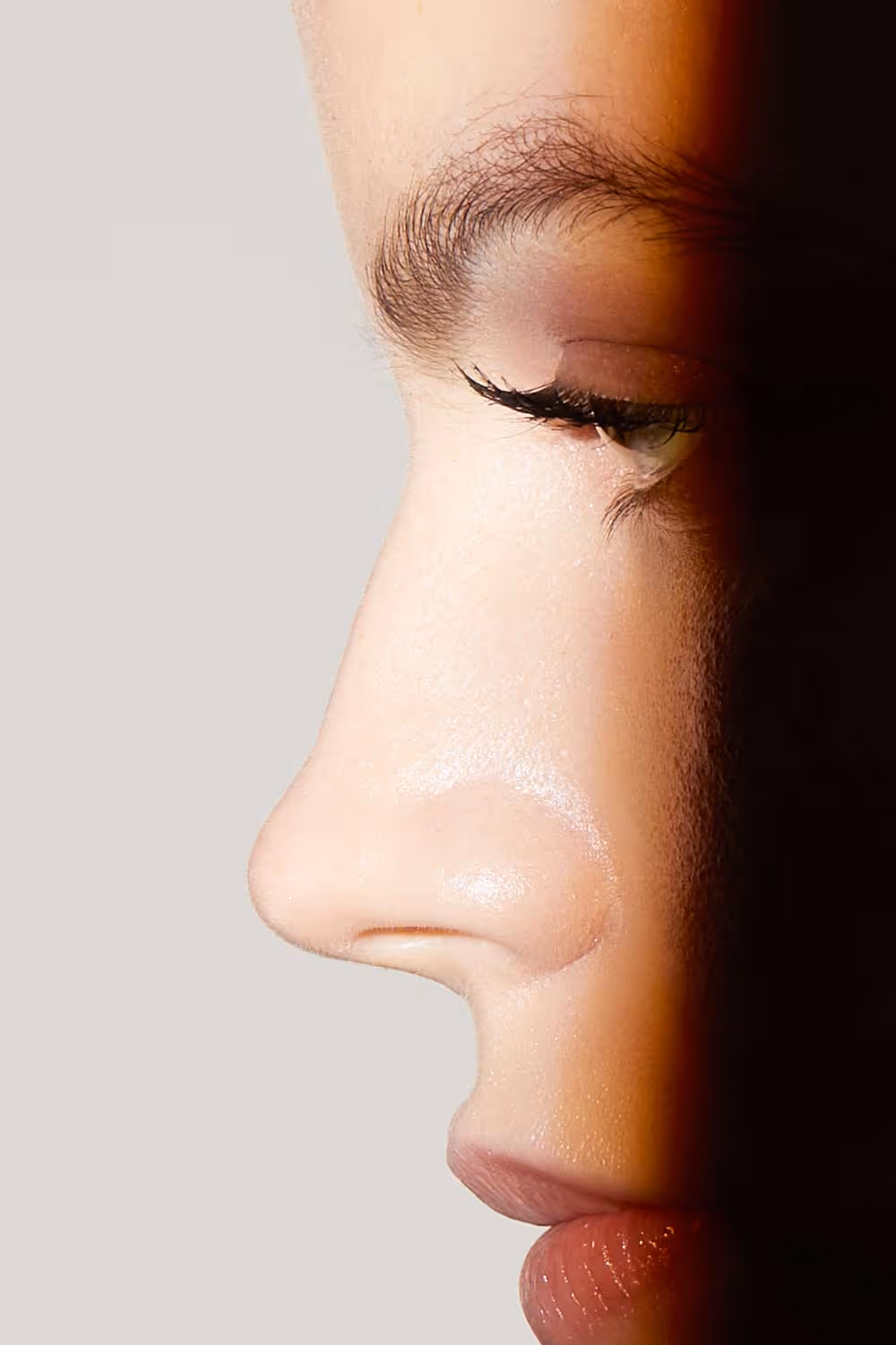 Close-up side profile of a person's face highlighting nose, closed eye with long lashes, and lips.