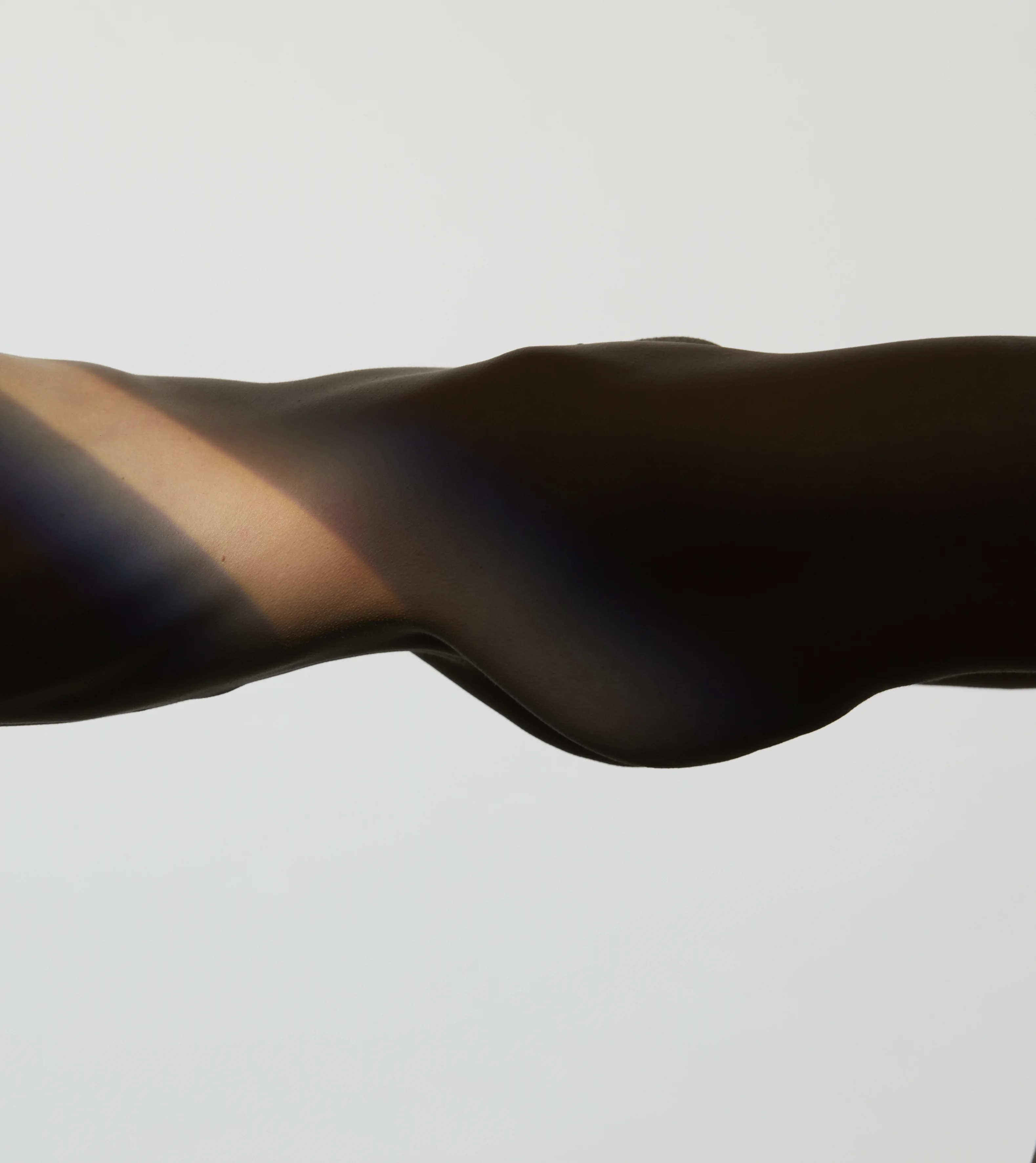 Seitliche Nahaufnahme von Bauch und Gesäß im Licht-Schatten-Spiel – Bodylift München Dr. Kleeberger