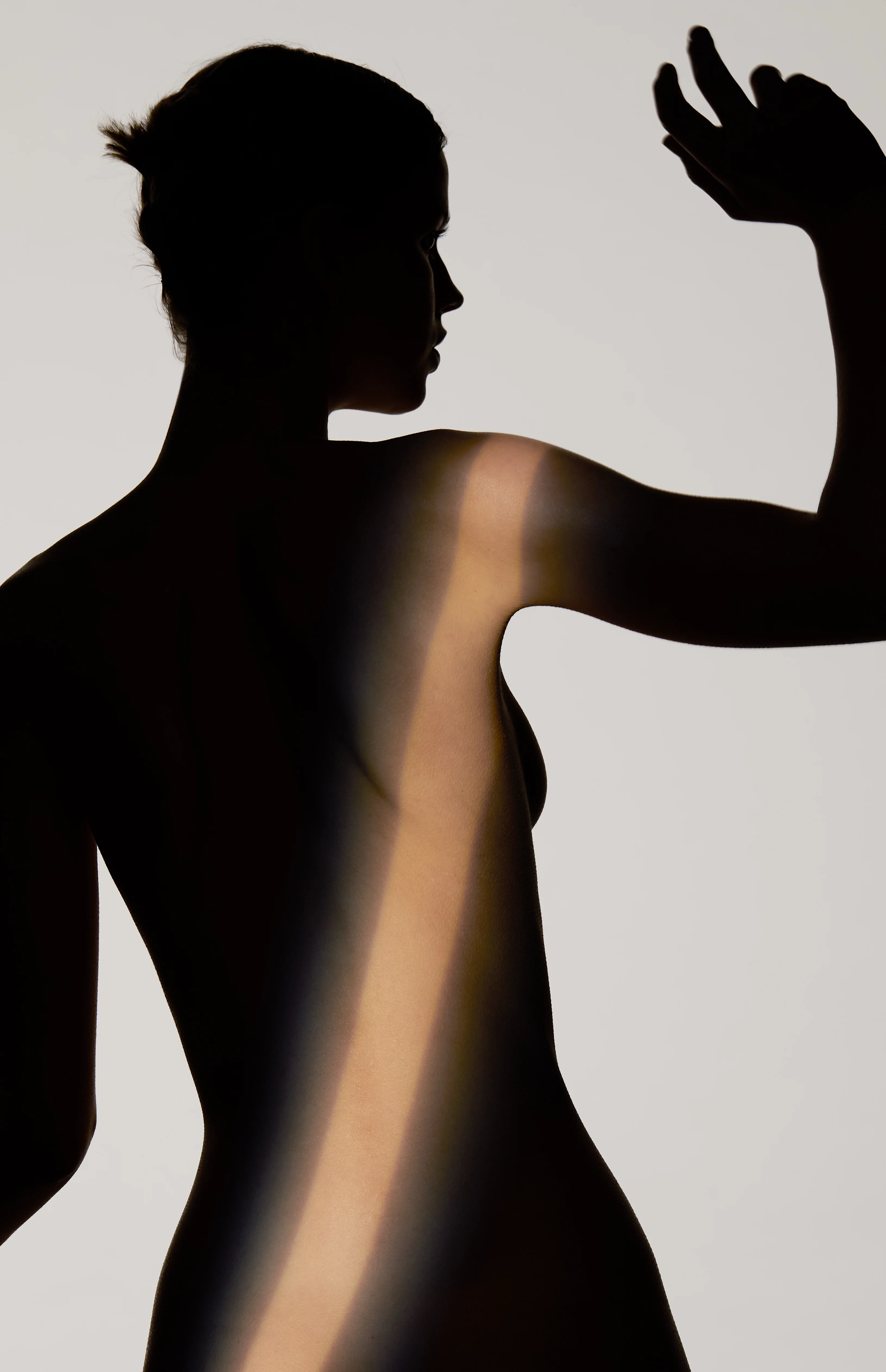 Silhouette einer Frau mit ausgestrecktem Arm im Licht-Schatten-Spiel – Lipödem Behandlung München Dr. Kleeberger