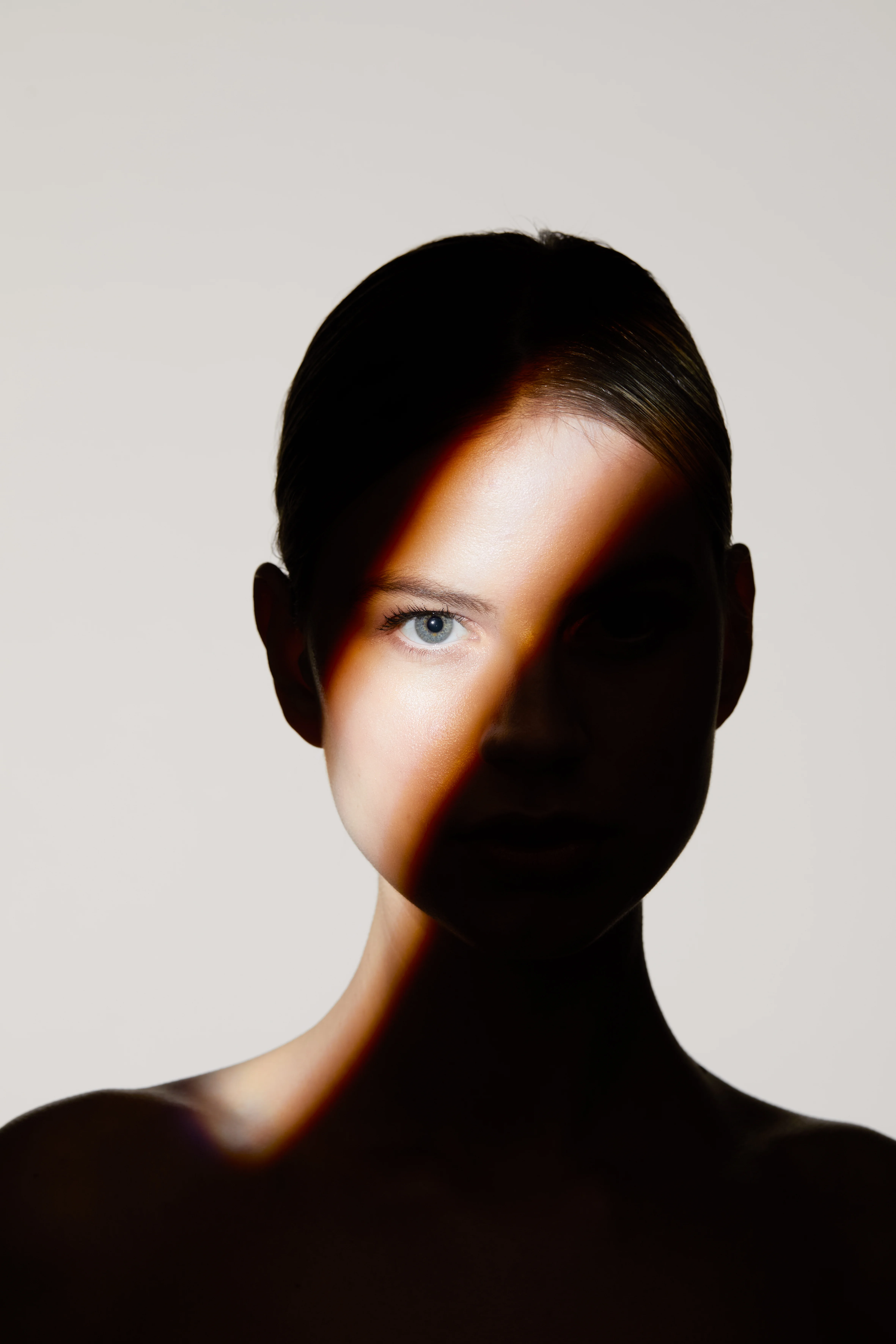 Porträt einer Frau mit Lichtstrahl über dem Gesicht im Licht-Schatten-Spiel – Narbenbehandlung München Dr. Kleeberger