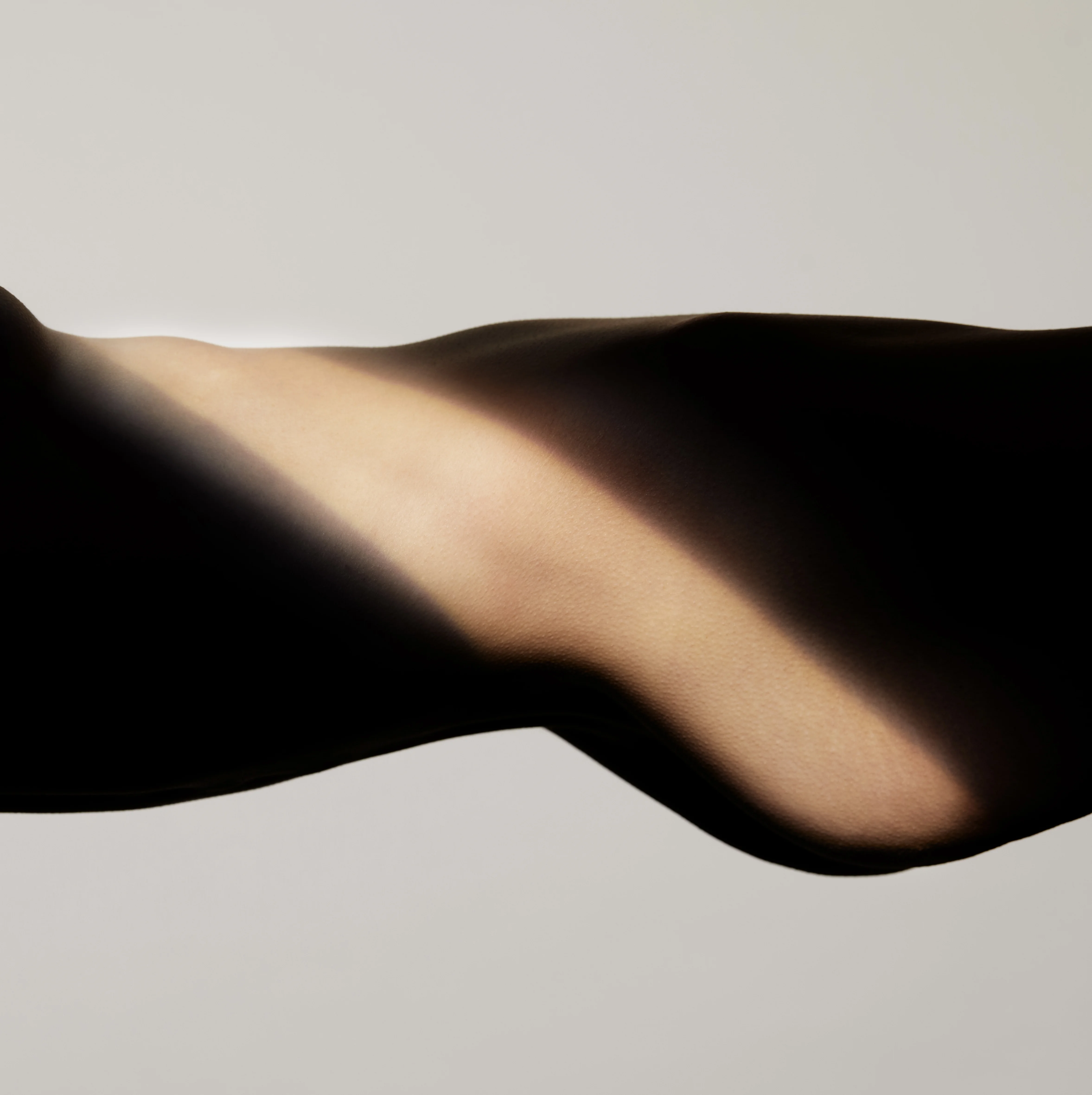 Ästhetische Silhouette eines Körpers im Profil mit Fokus auf die harmonische Kontur von Taille und Hüfte nach einer Fettabsaugung (Liposuktion), betont durch einen diagonalen Lichtstrahl.
