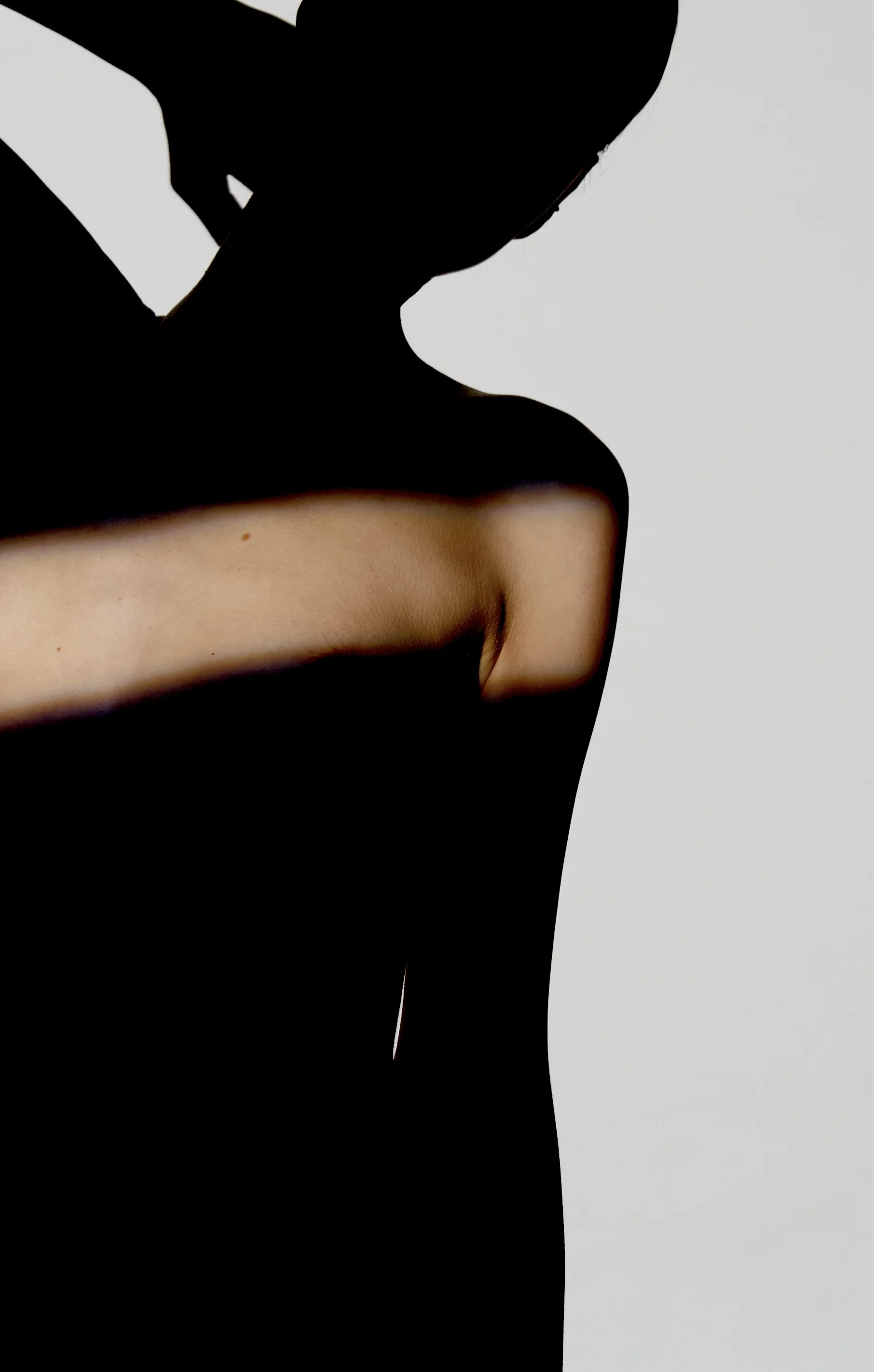 Künstlerische Silhouette eines Oberkörpers von der Seite vor hellem Hintergrund, bei der ein gezielter Lichtstreifen die Schulter- und Brustpartie hervorhebt – zur Veranschaulichung einer Brustverkleinerung oder ästhetischen Brustreduktion.