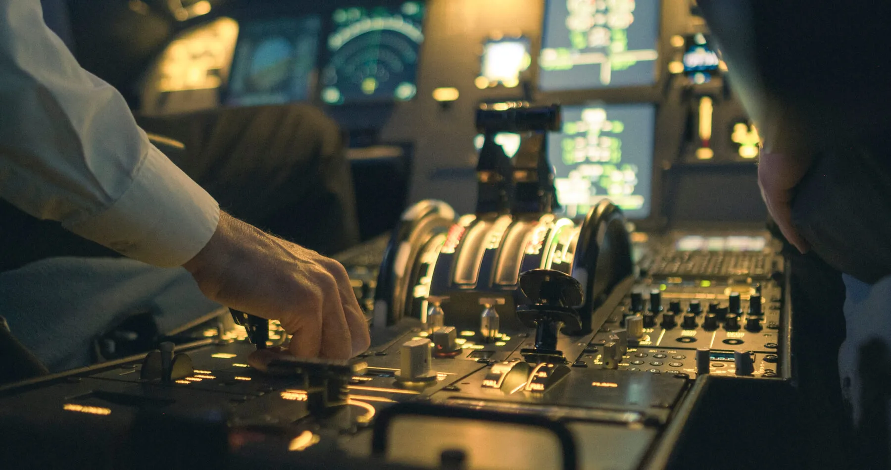Pilots' hands on the thrust levers in an airliner simulator cockpit