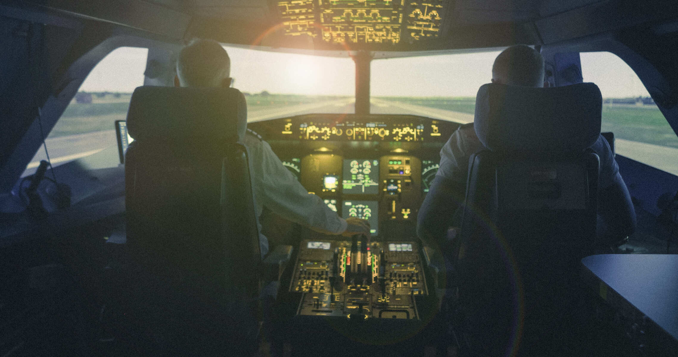 View from behind two pilots in an airliner cockpit during approach
