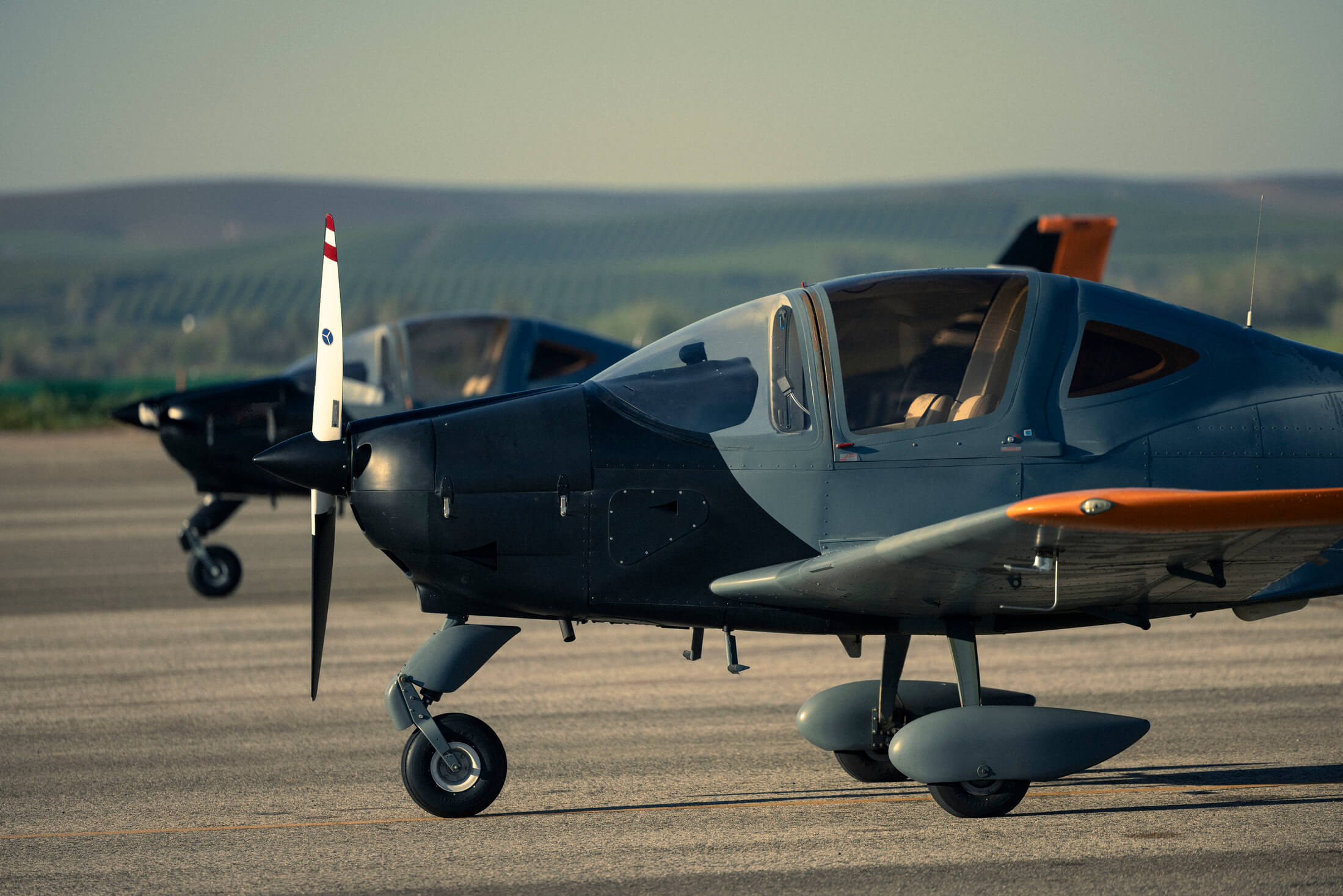 Two Greybird single-engine training aircraft parked on the apron