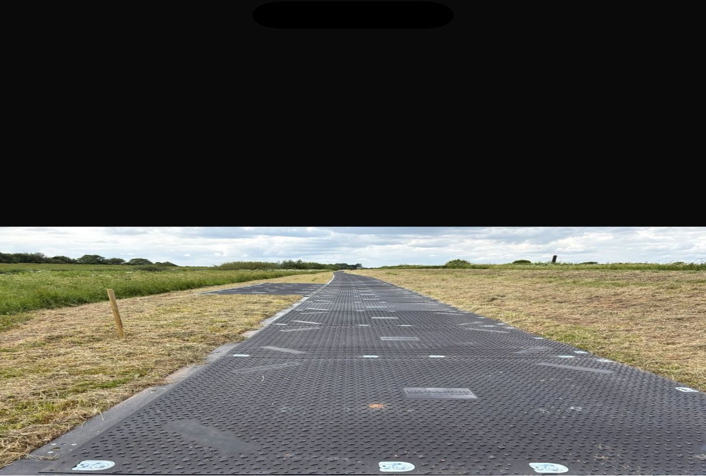 A wide view of the installed temporary trackway supporting safe movement across the Dutch River embankment repair site.