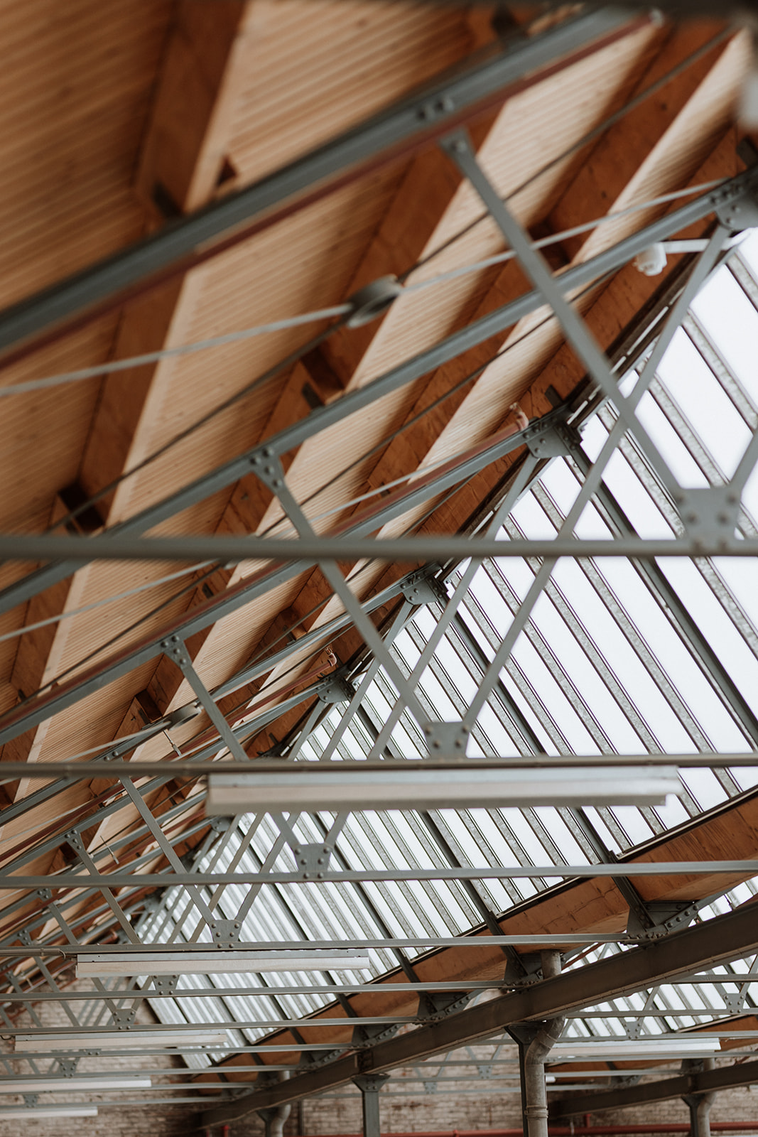 Stalen spanten, houten dakbeschot en glazen lichtstraat in een bestaand gebouw.