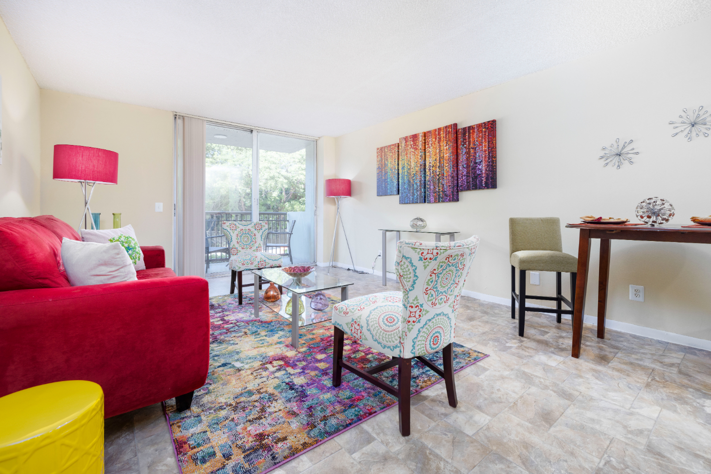 Living area with sofa and balcony doors with view of dining area with table and chairs