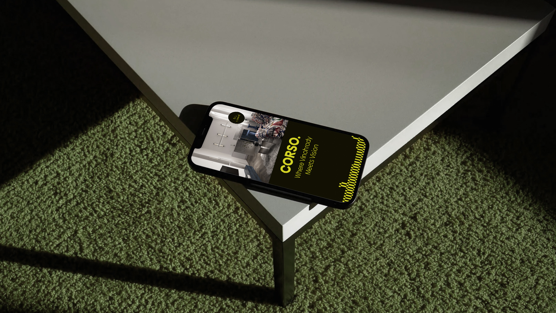 Smartphone on table showing 'CORSO. Where Vinohrady Meets Vision' with interior design image.