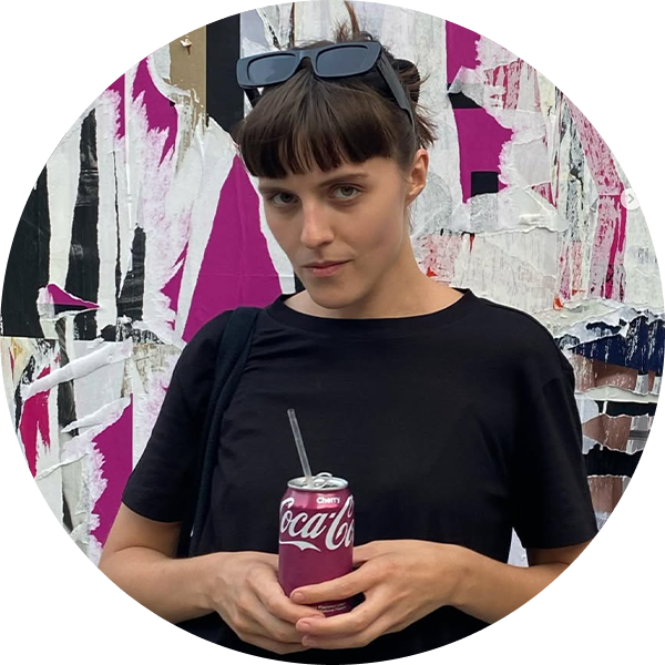 Woman wearing black shirt and sunglasses on head holds a Cherry Coca-Cola can with a straw.