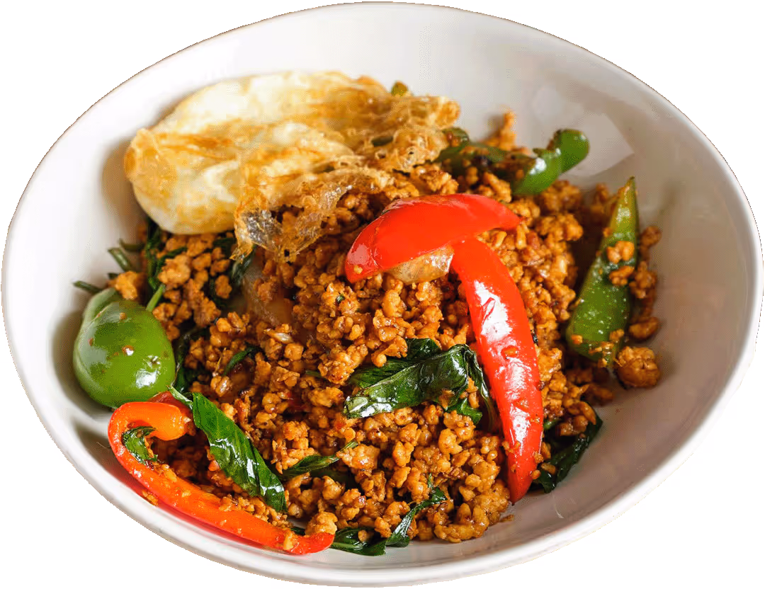 Bowl of minced meat with red and green peppers, basil leaves, and a fried egg on top.