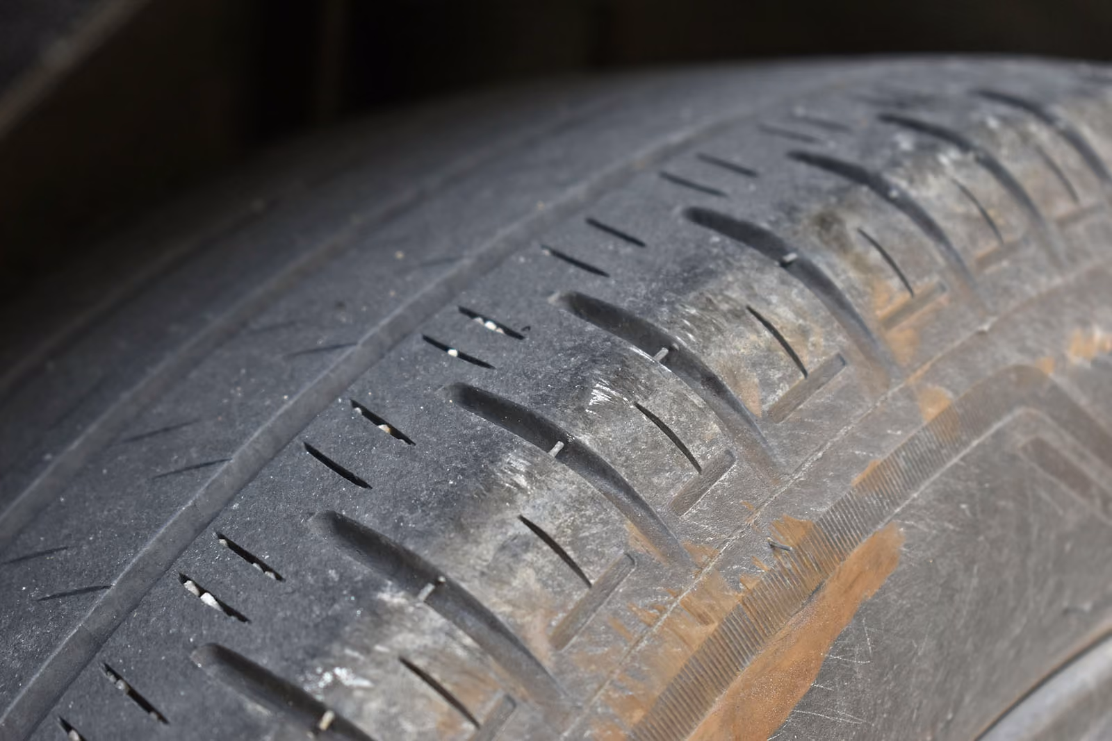 Close-up of a worn car tire tread showing minimal depth and signs of wear.