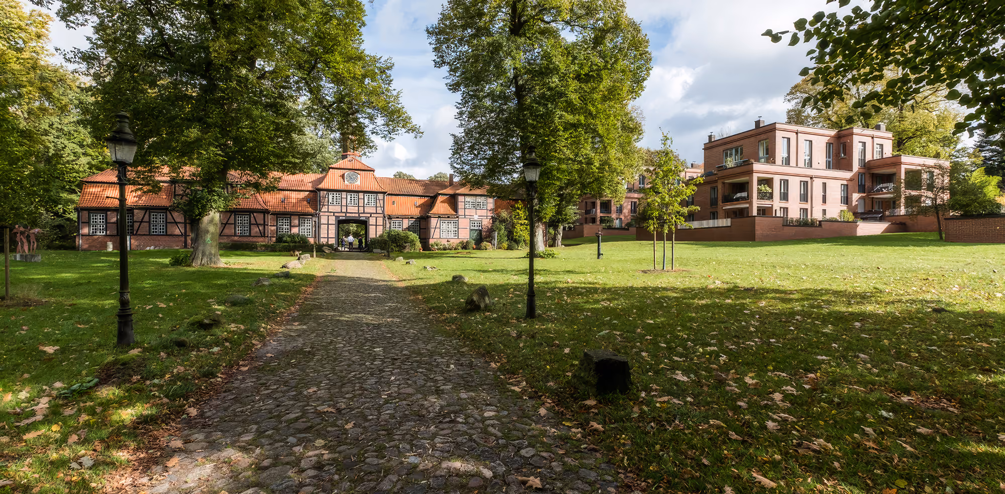 Modernes Einfamilienhaus mit Garage, Garten, Terrasse mit Möbeln und blauem Himmel.