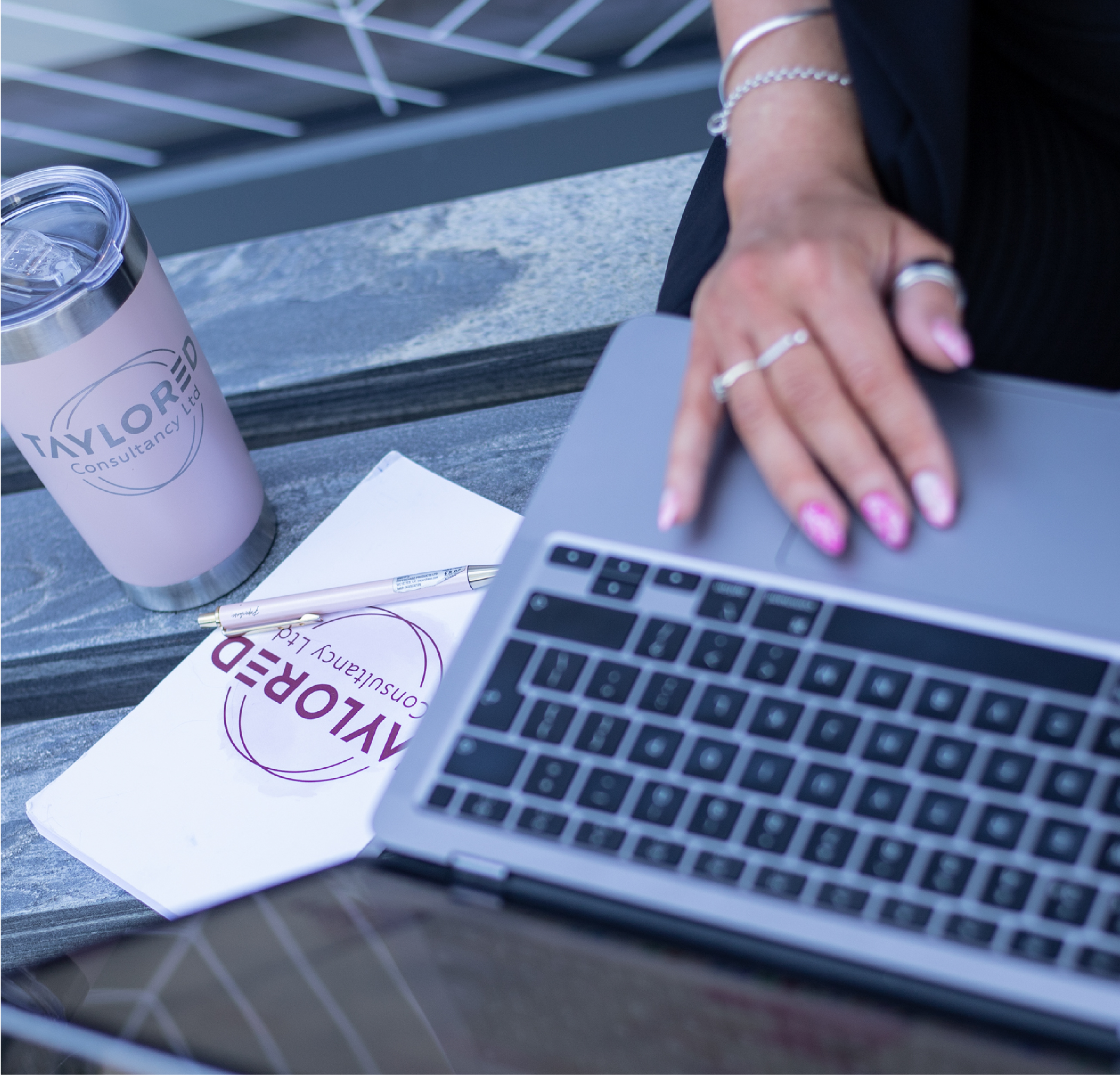 Consultant working on a laptop with Taylored Consultancy branded merchandise