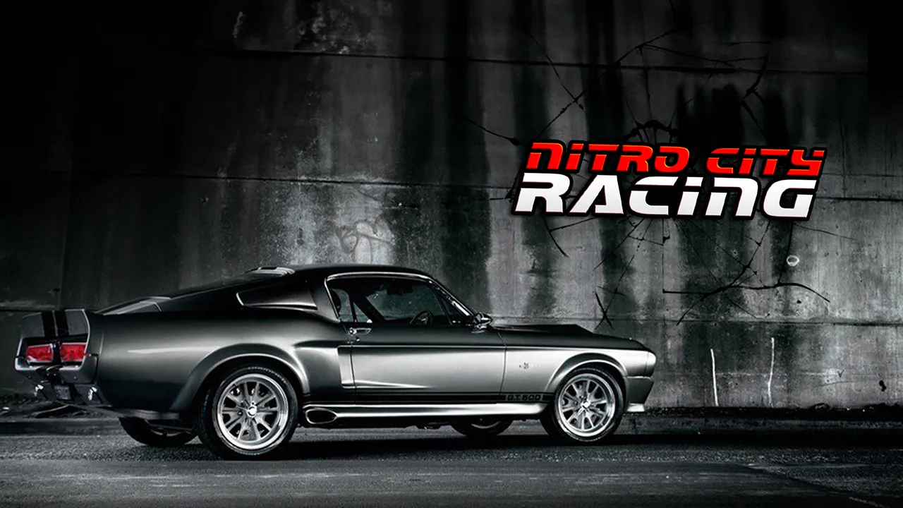 Side view of a gray classic muscle car parked in front of a concrete wall with Nitro City Racing text.