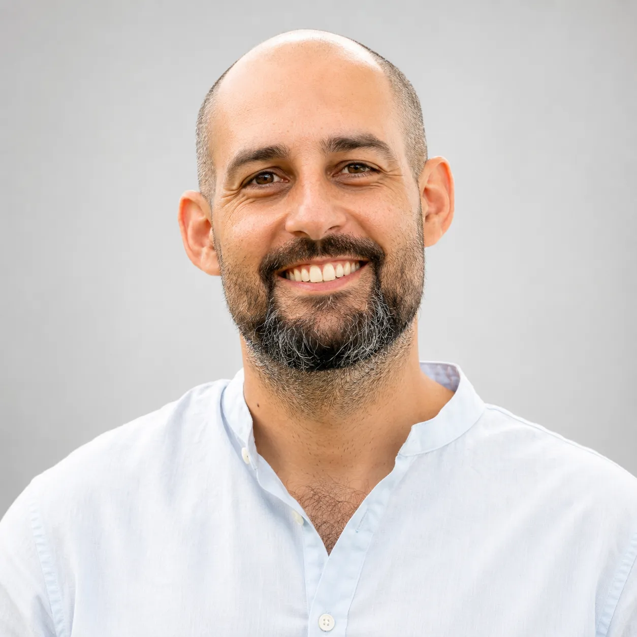 Man with beard wearing a white shirt against a light gray background.